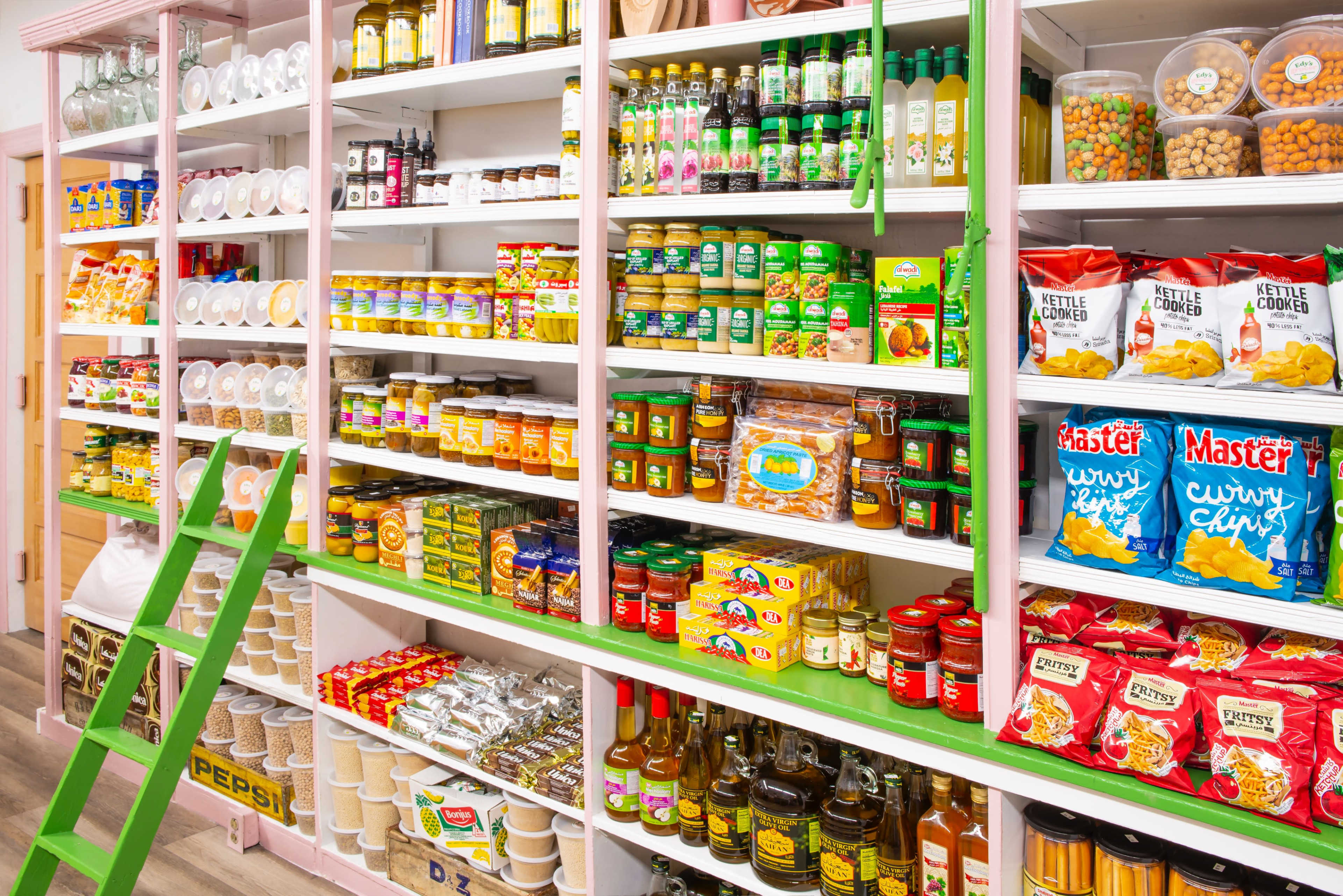 A brightly lit grocery store aisle features neatly arranged shelves stocked with various canned goods, snacks, and dry ingredients.