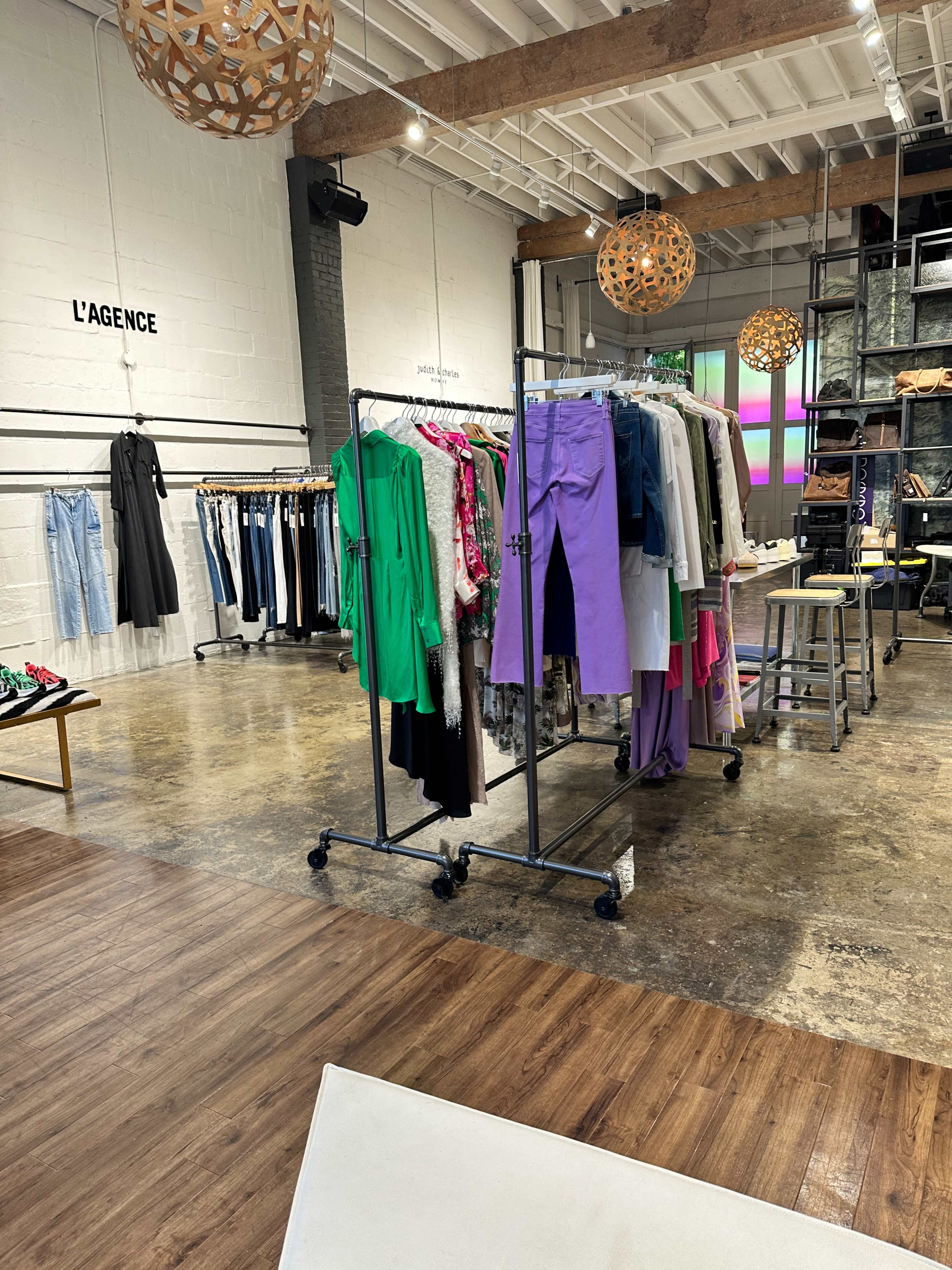 A stylish clothing store display featuring colorful garments hanging on a rack, with a modern interior design and decorative pendant lights overhead.
