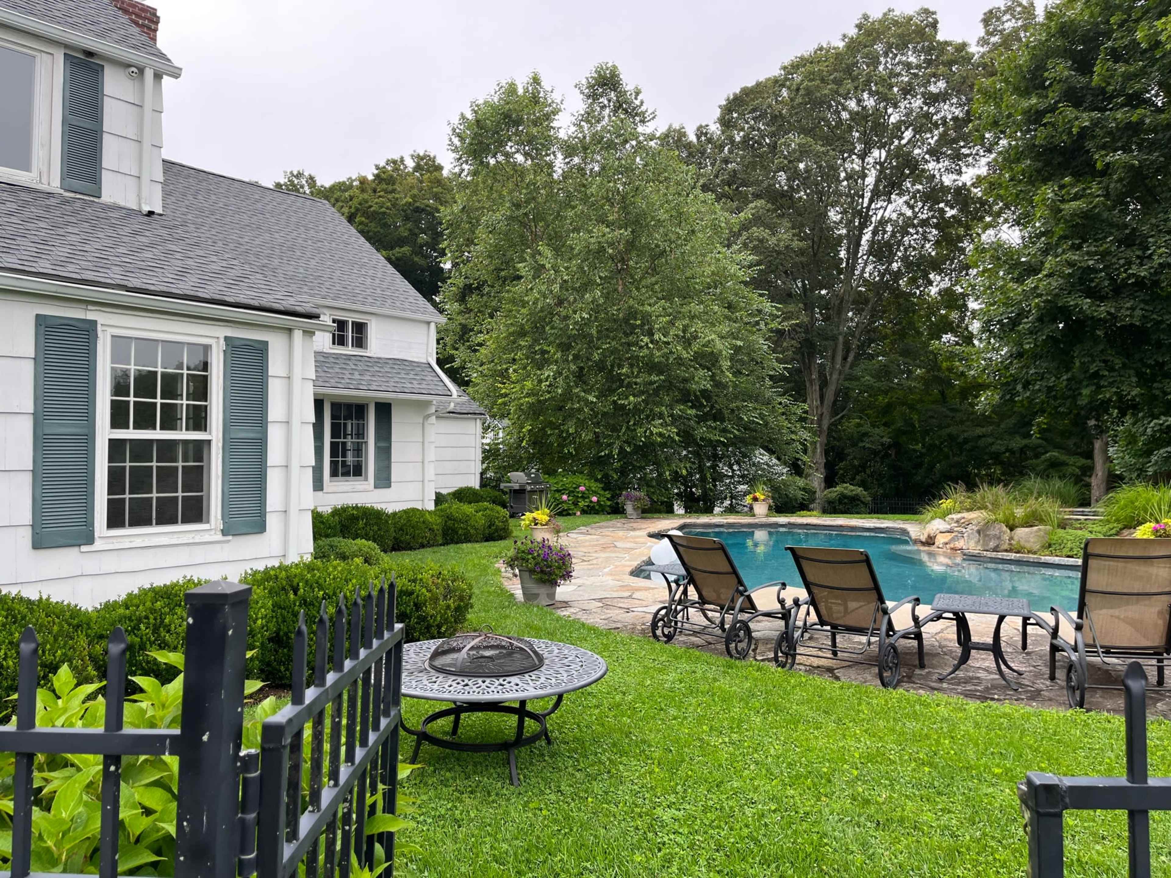 A well-maintained backyard features a swimming pool surrounded by lounge chairs and green landscaping.