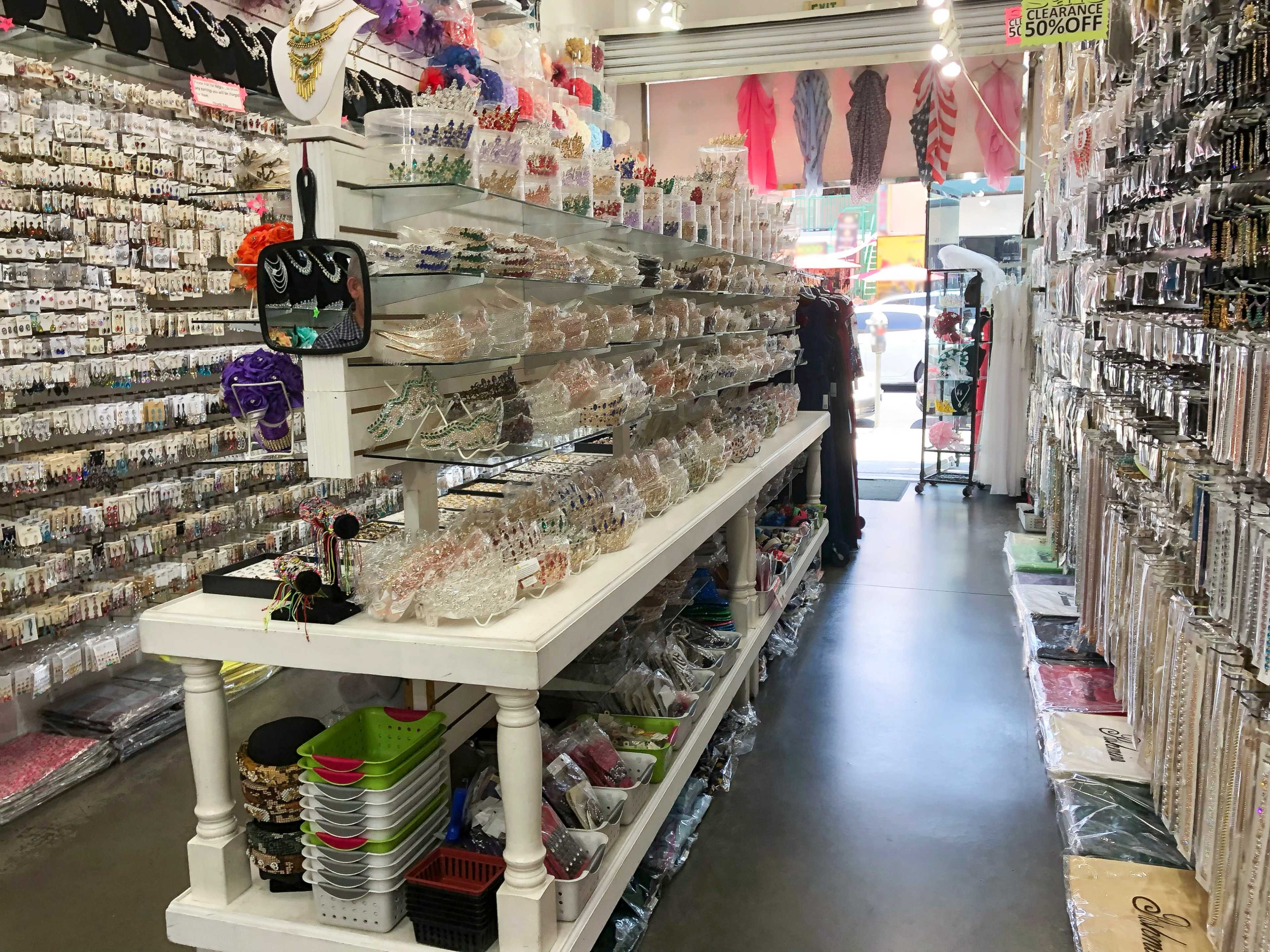 The image shows a craft supply store aisle filled with various beads and embellishments on white shelving units.