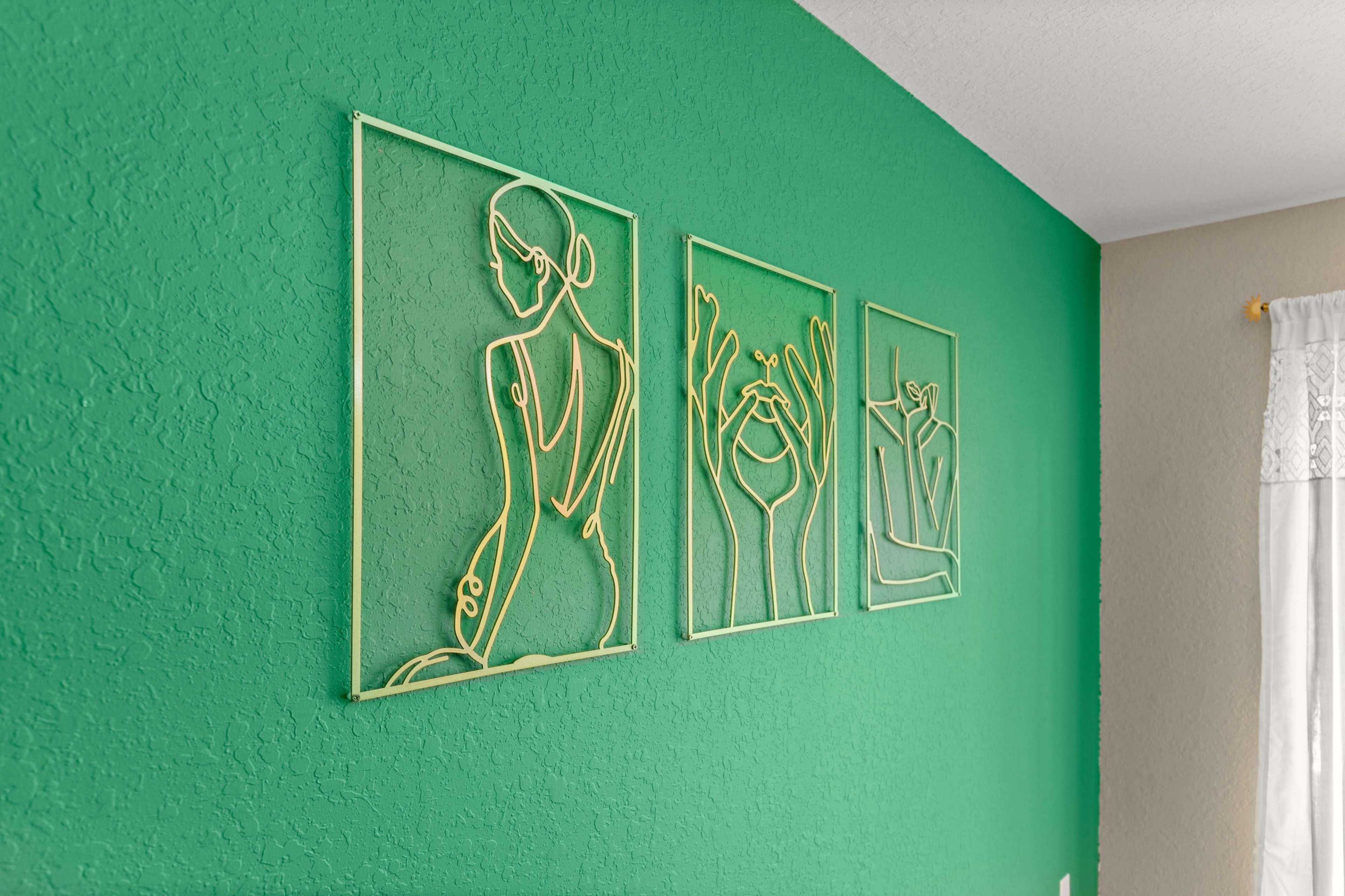 Three wire art pieces mounted on a vibrant green wall.