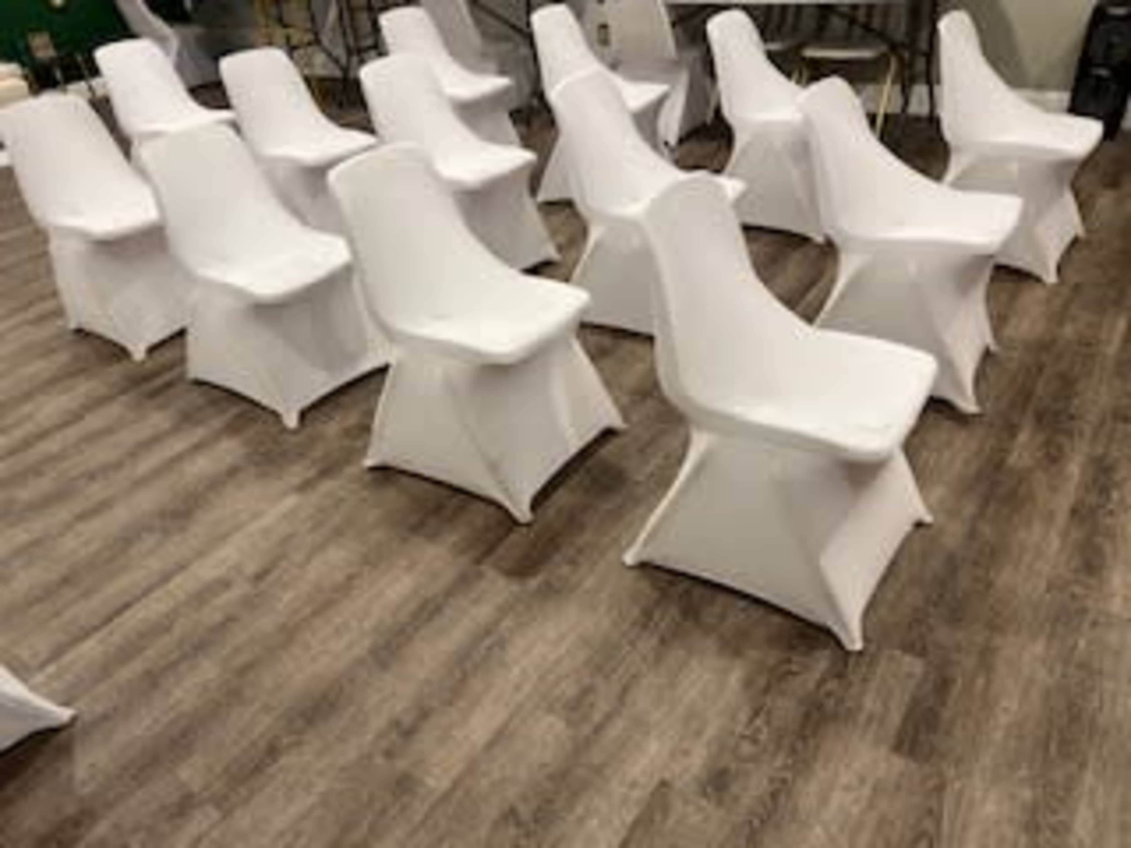 The image shows a row of white chairs arranged in a space with wooden flooring.