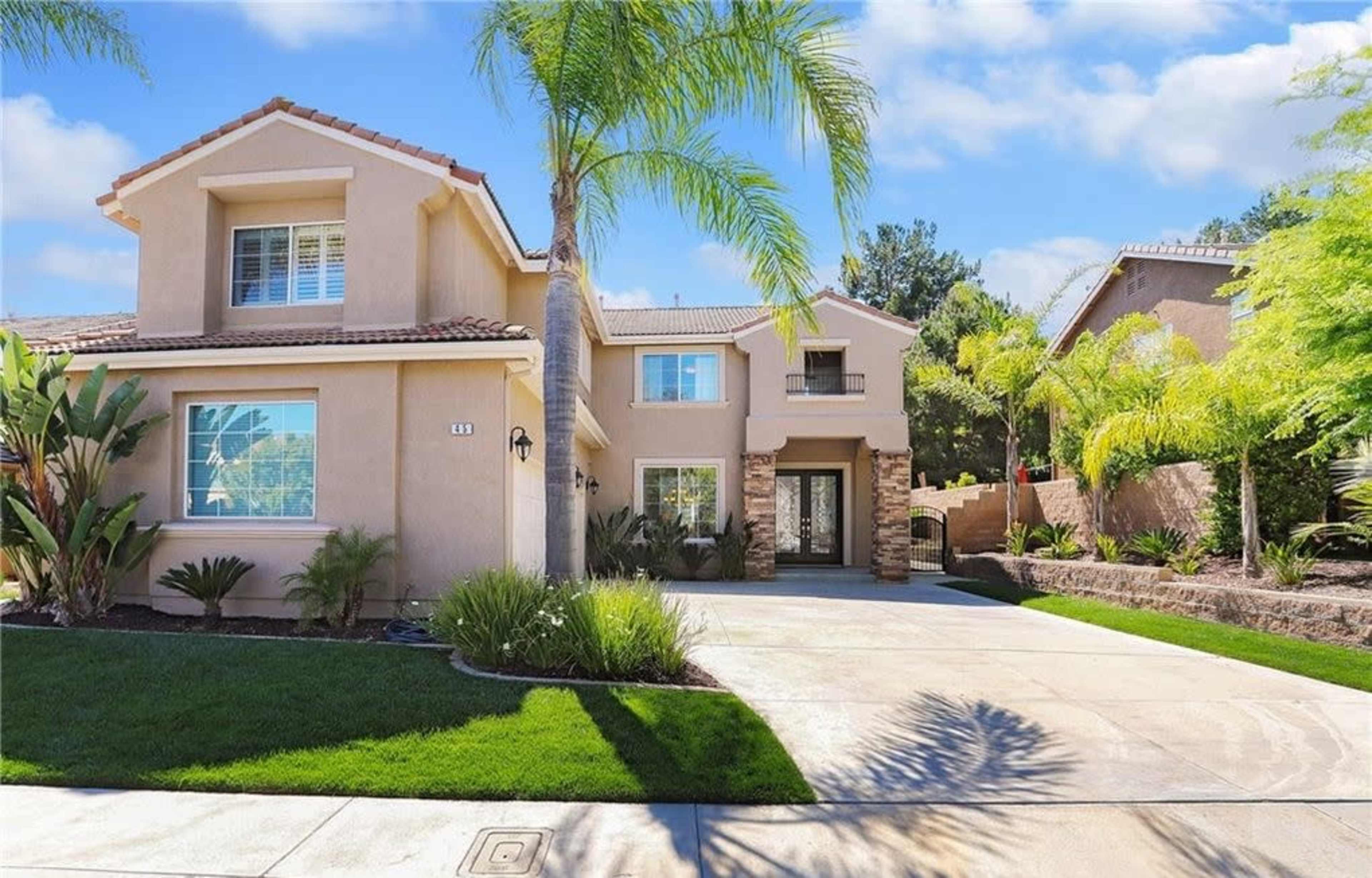 A two-story suburban house with a landscaped front yard and a paved driveway.