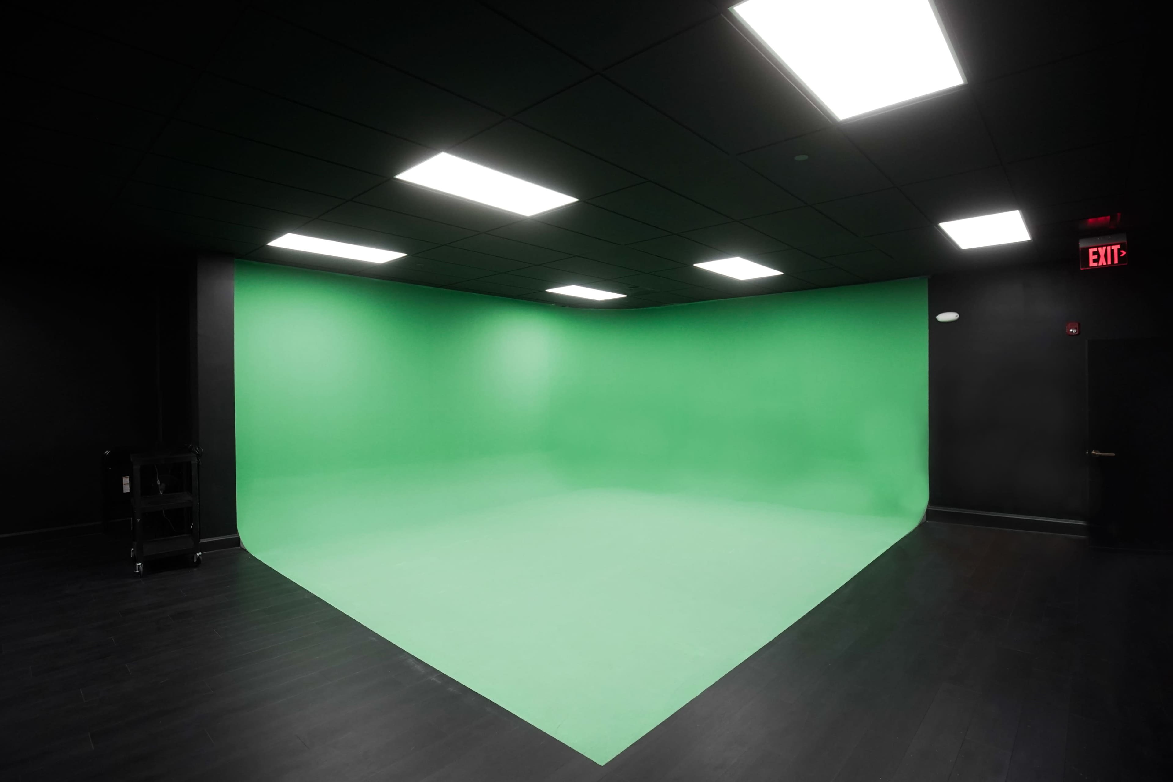 A green screen setup in a dark room with overhead lights.