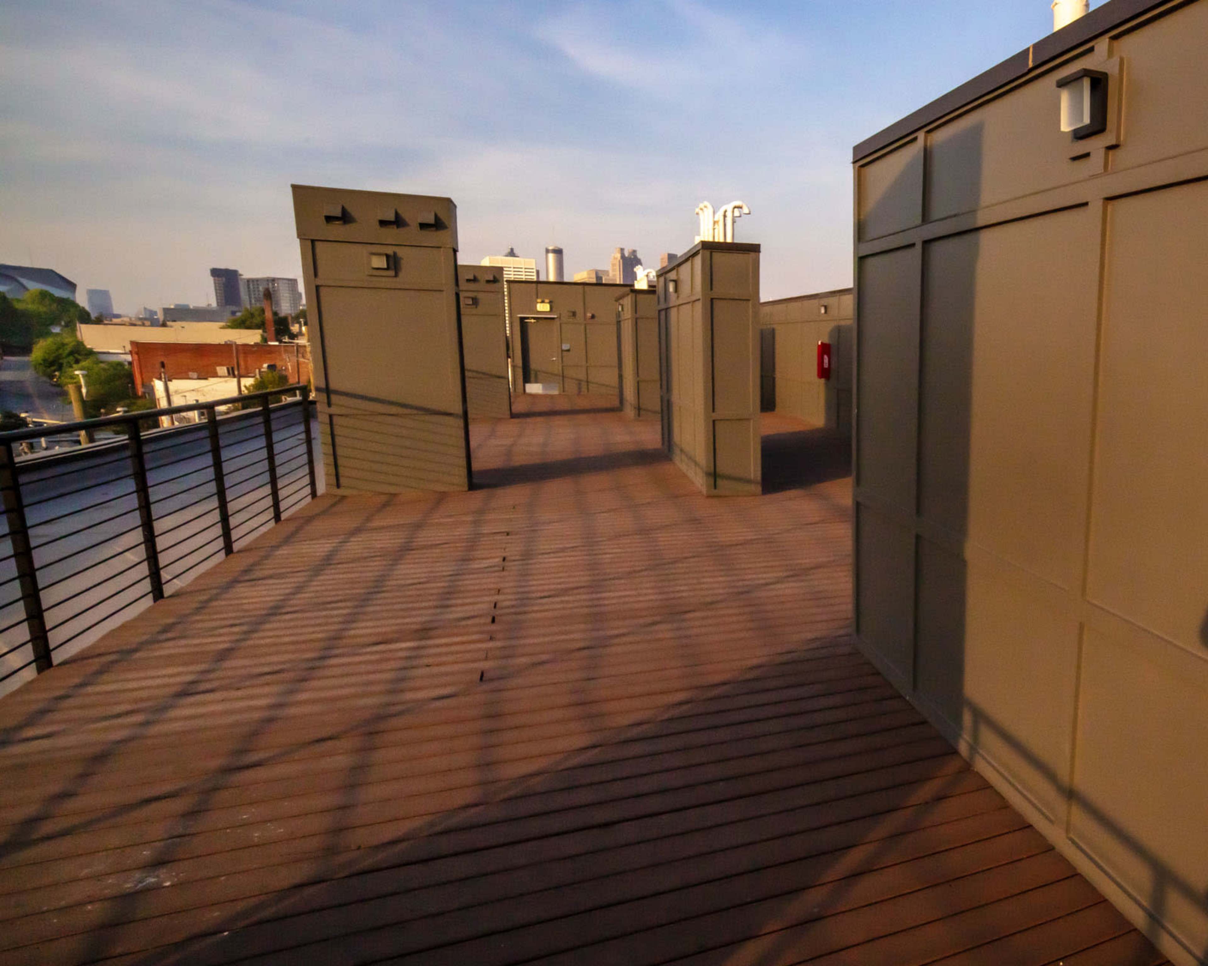 The image shows a wooden deck area with gray walls and railings, set against a backdrop of a city skyline.