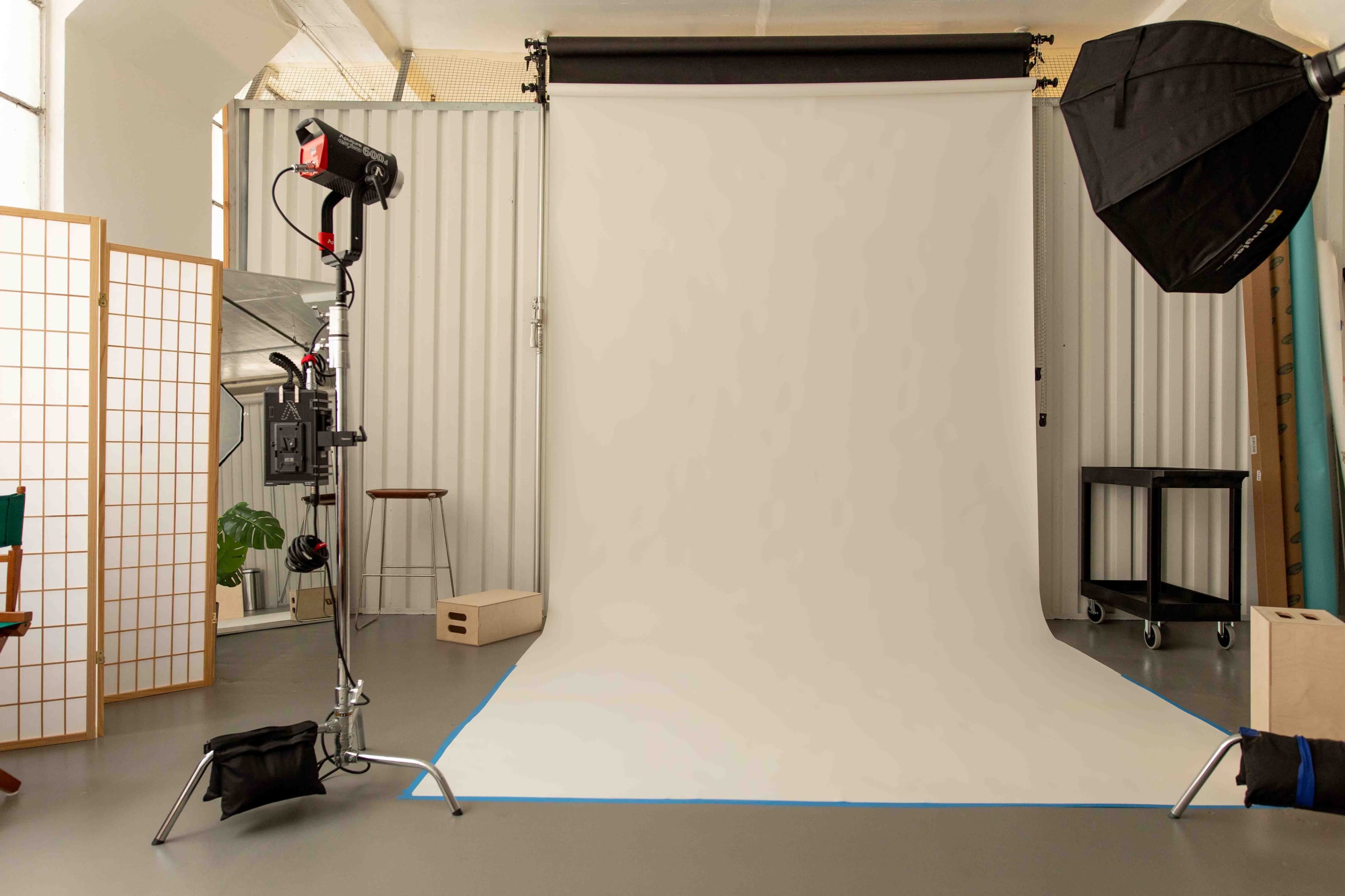 A photography studio with a neutral backdrop, lighting equipment, and various props arranged in an organized manner.