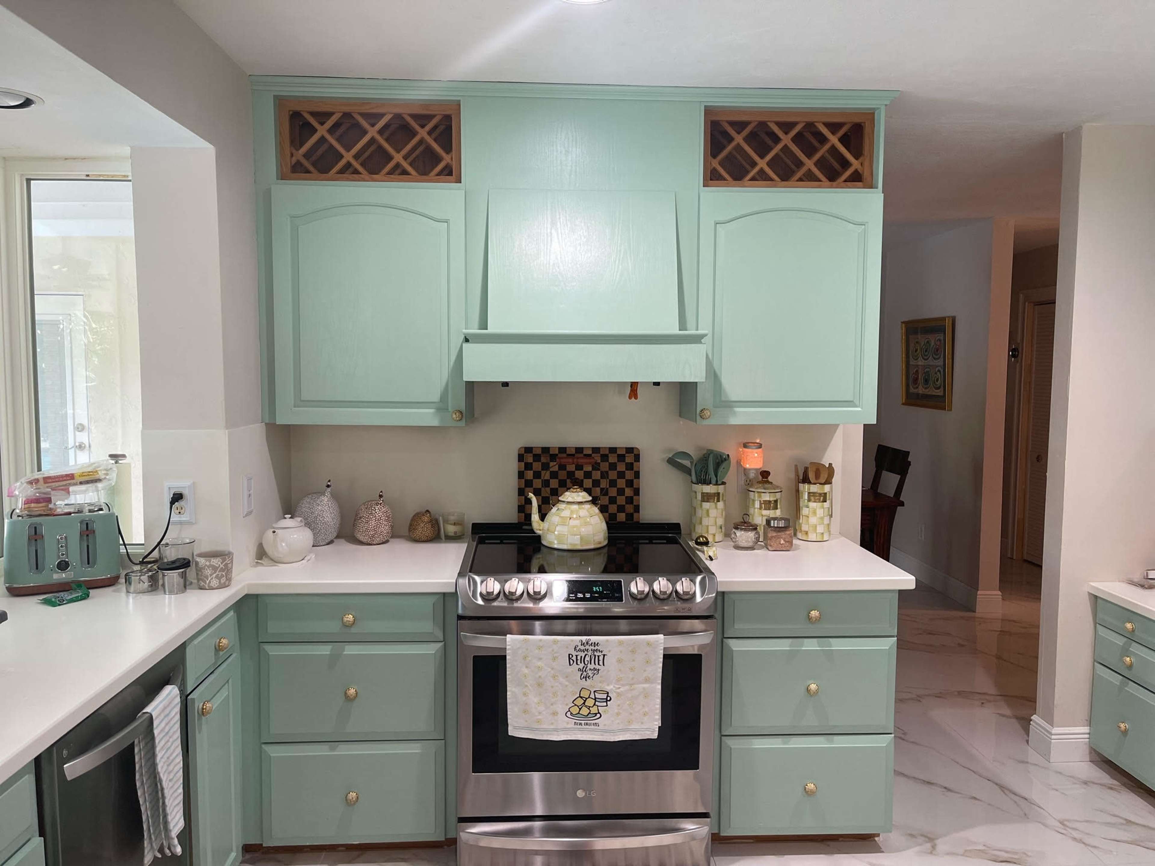 The image shows a kitchen with mint green cabinetry, a stainless steel stove, and decorative items on the countertops.
