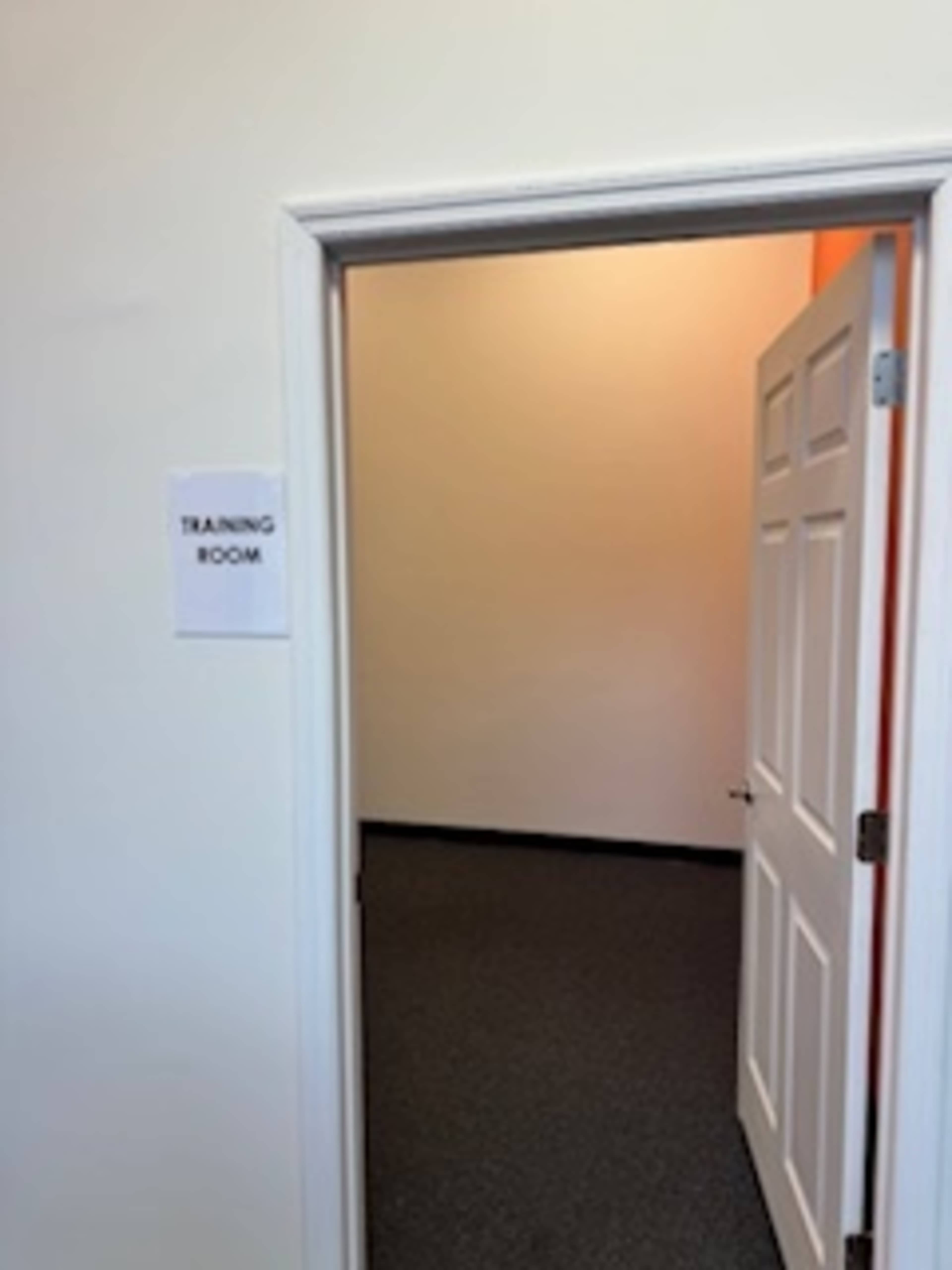A doorway opens into an empty training room with a sign indicating its purpose.