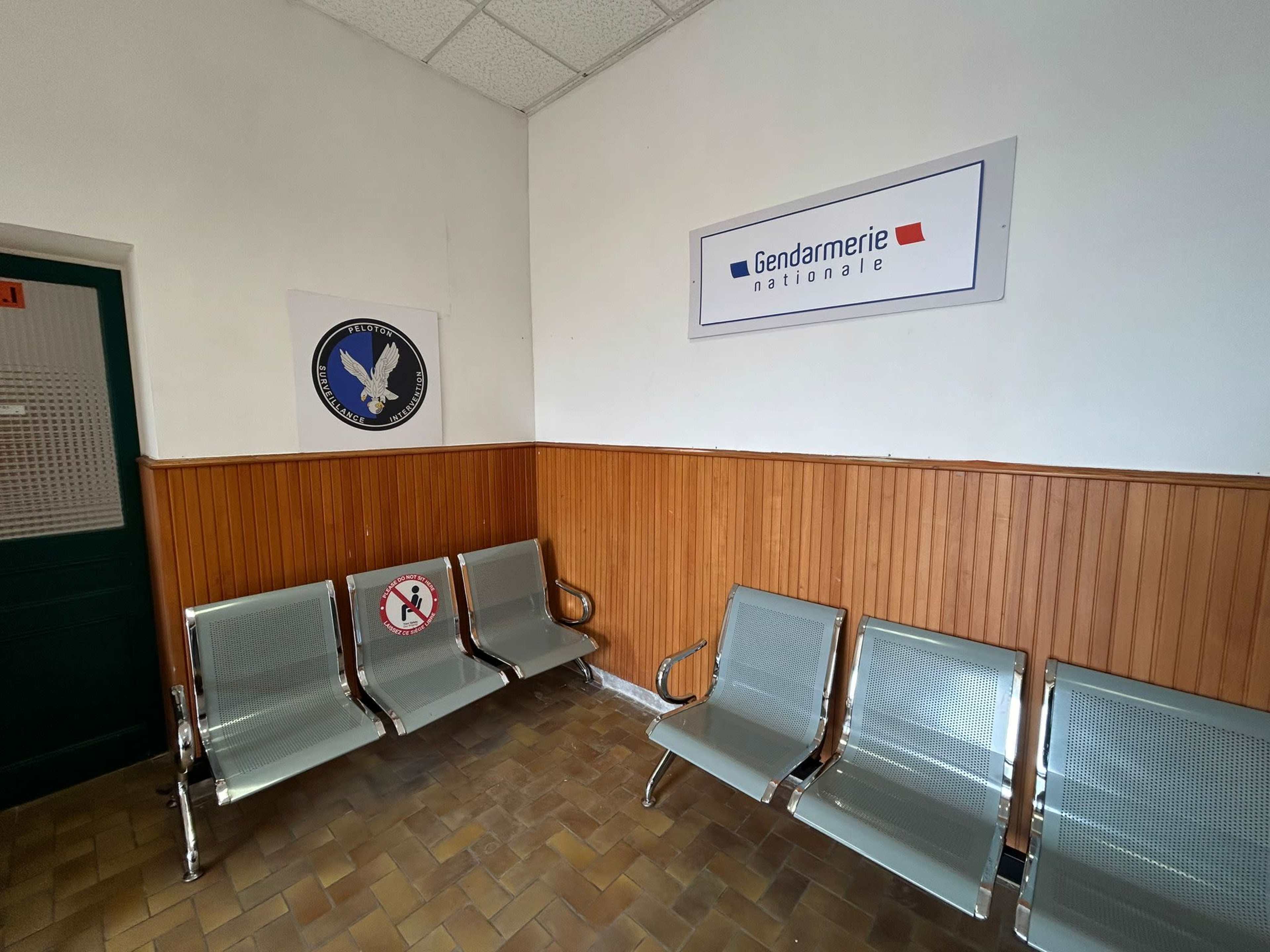 A waiting area with metal benches and signs indicating a Gendarmerie Nationale office.