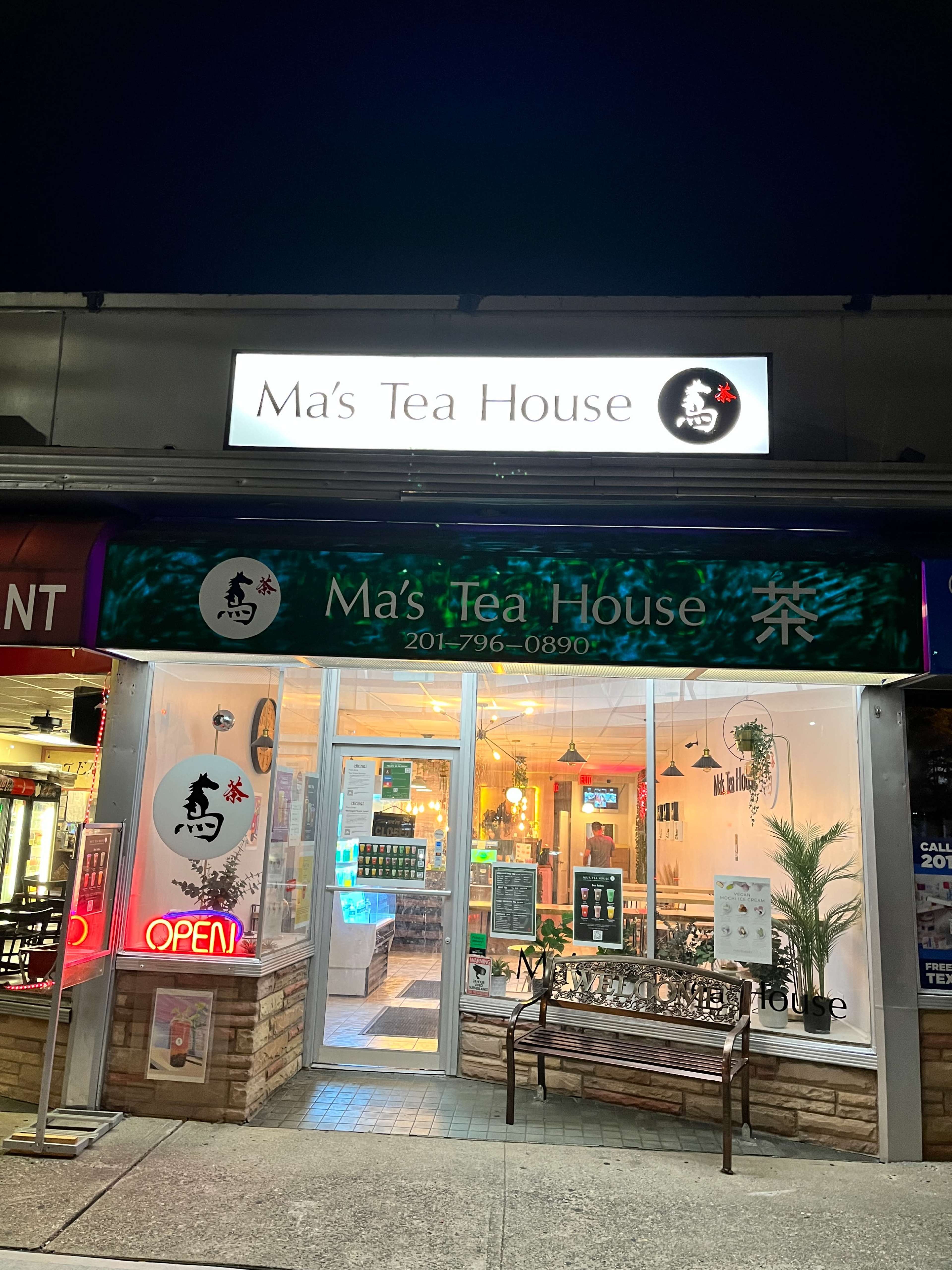 The exterior of Ma's Tea House illuminated at night with a visible sign and an open doorway.