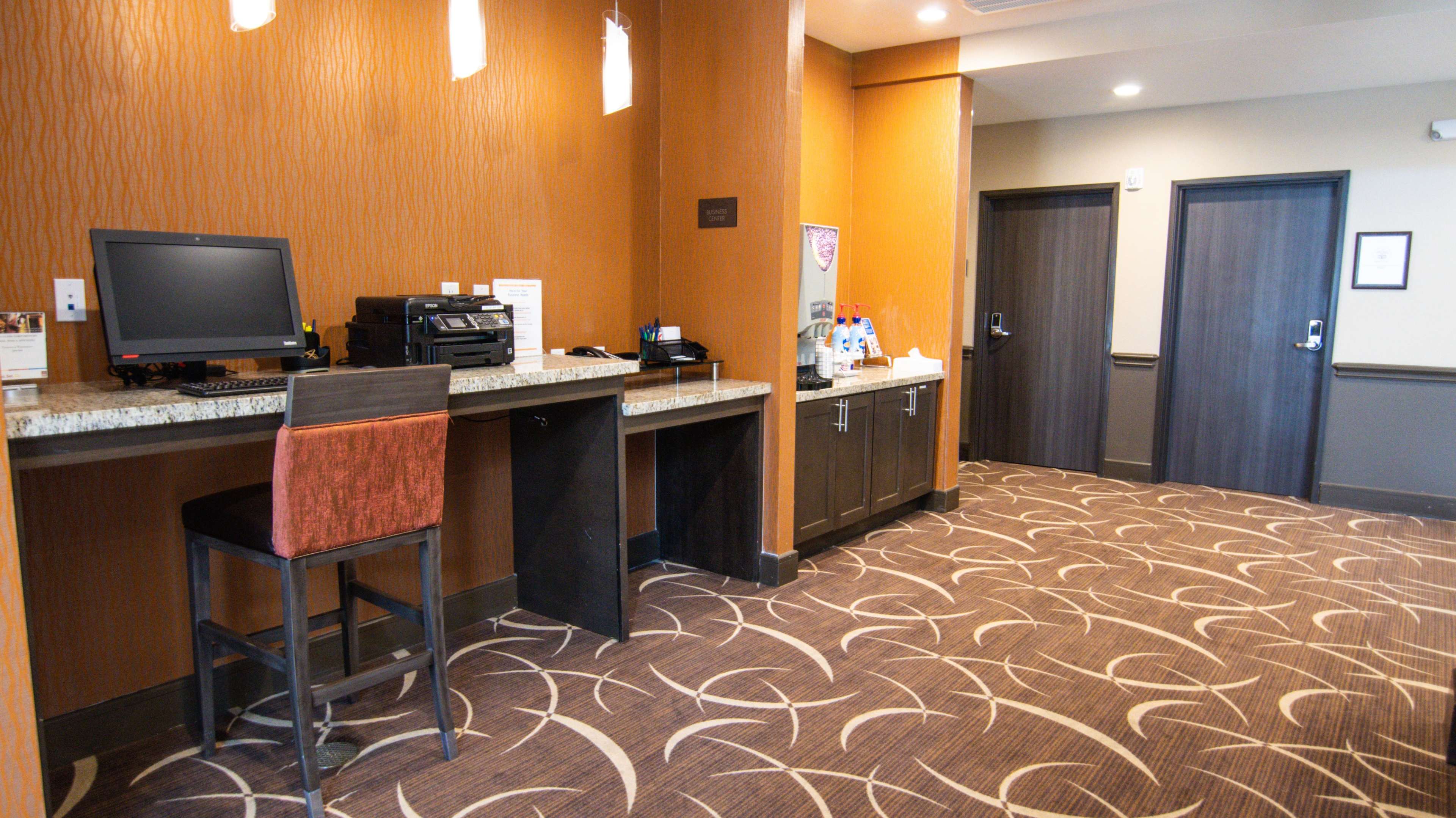 A check-in area of a hotel with a computer station, printer, and two doors leading to guest rooms.