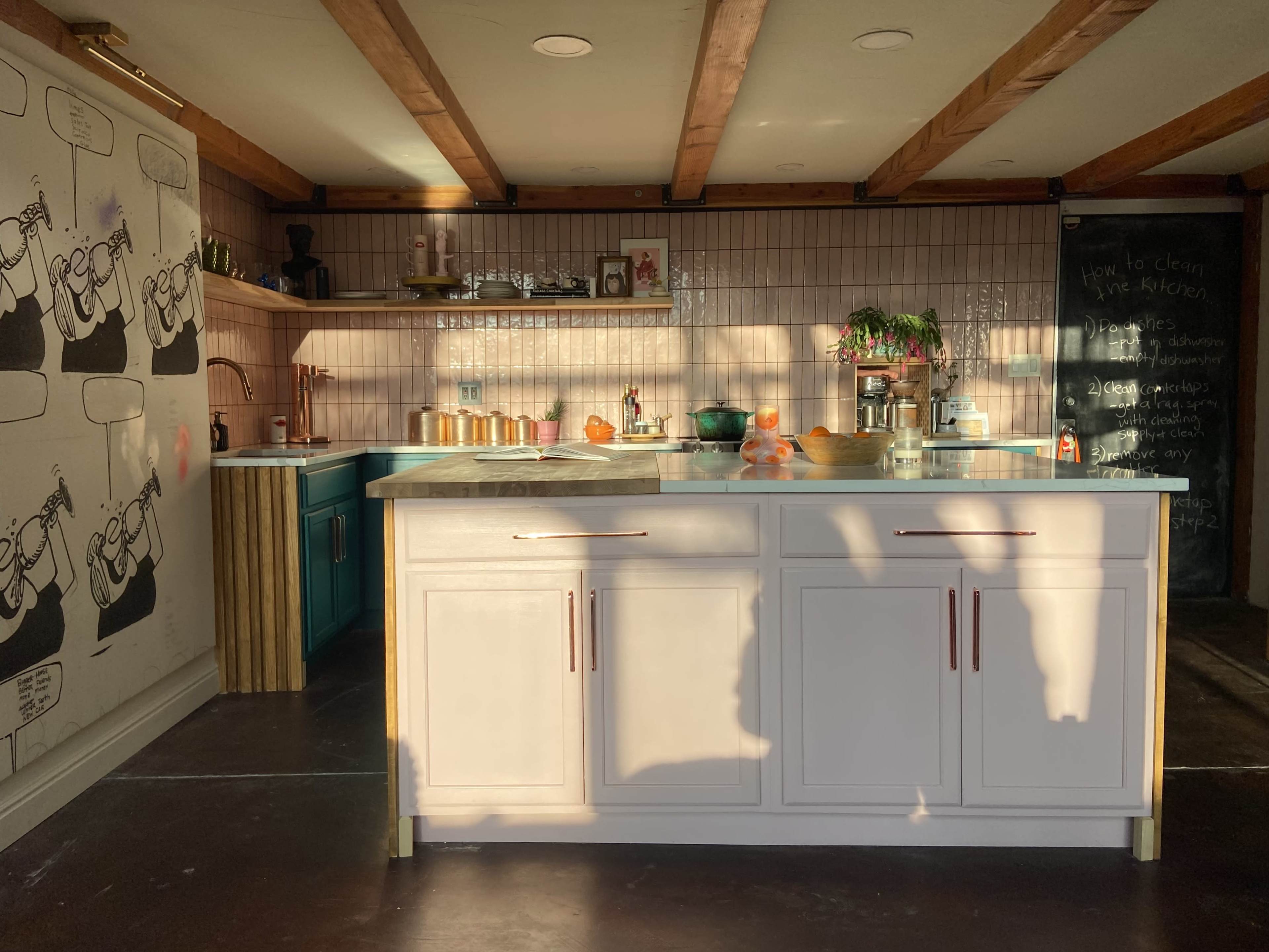 A well-lit kitchen with a white island, wooden beams on the ceiling, and various kitchen items arranged on the counters.