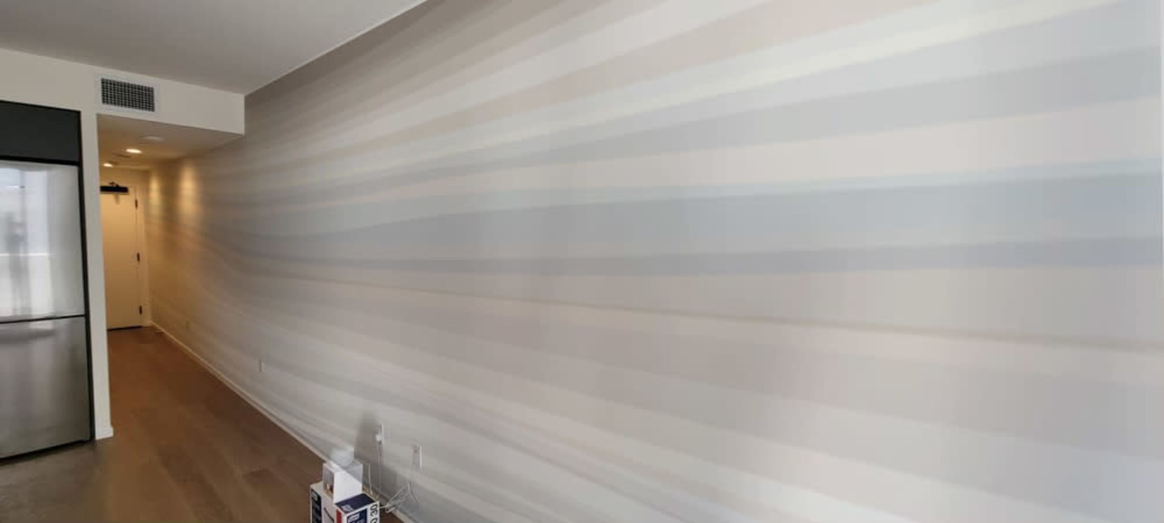 A smooth wall with a horizontal gradient pattern in light colors is shown next to a metallic kitchen appliance.