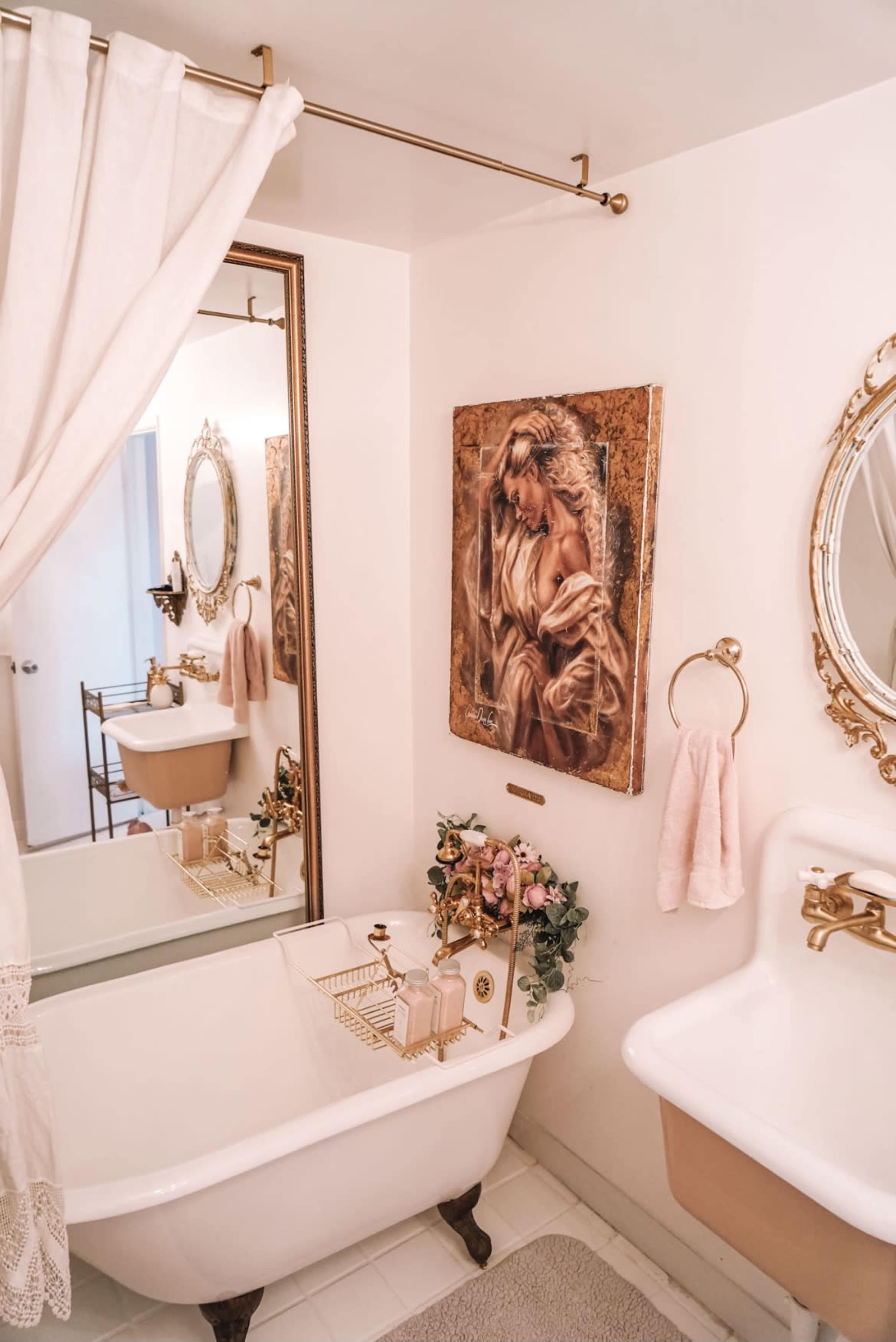 A bathroom with a vintage clawfoot bathtub, a large mirror, and a decorative painting on the wall.
