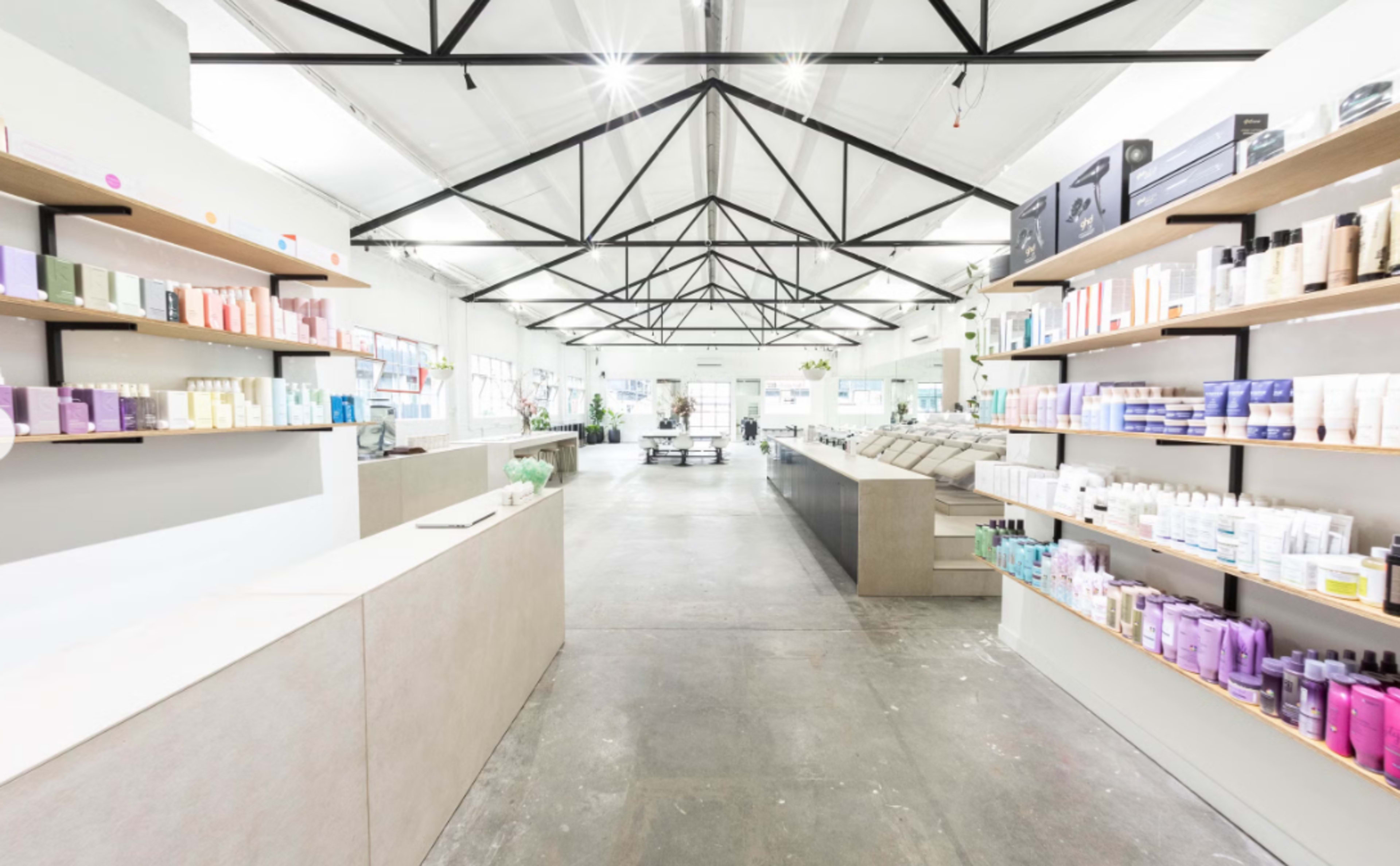 The image shows a spacious interior of a retail store with product shelves on both sides and a modern counter at the front.