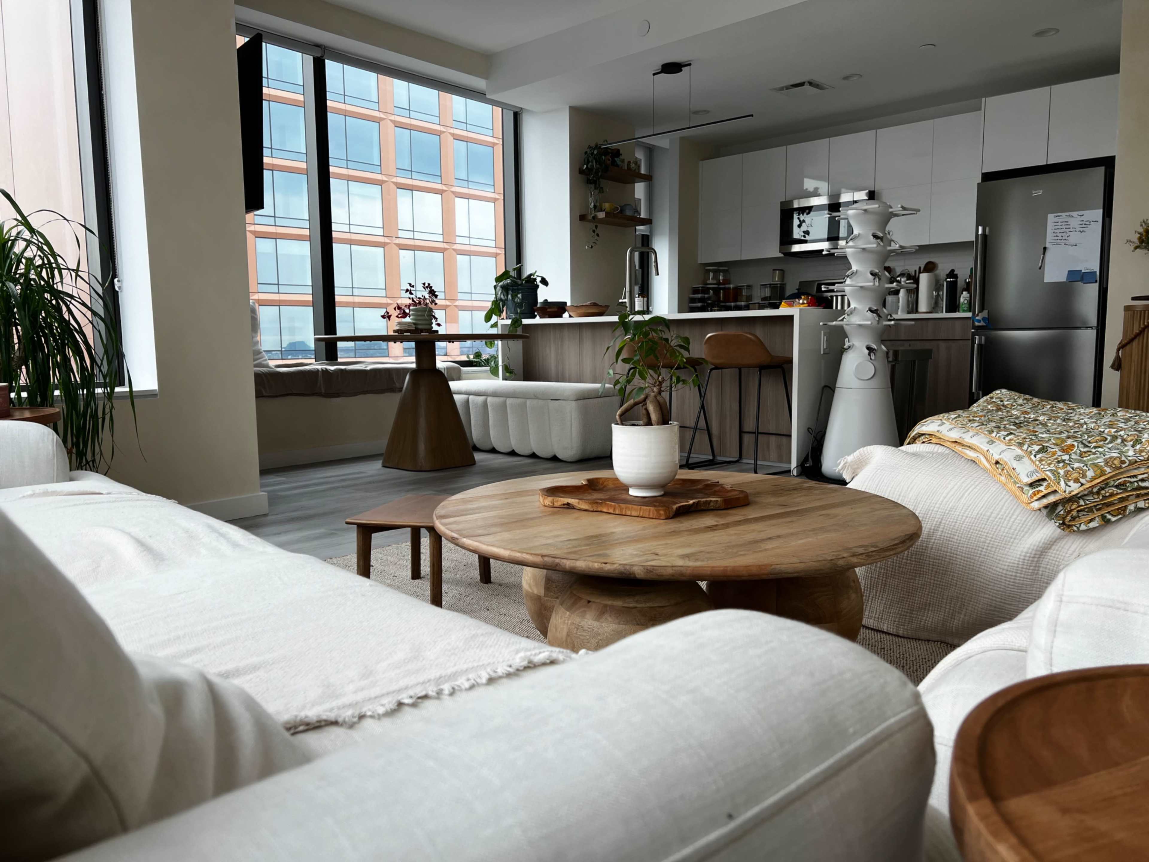 A modern living room with a light-colored sofa, a wooden coffee table, and an open kitchen area visible in the background.