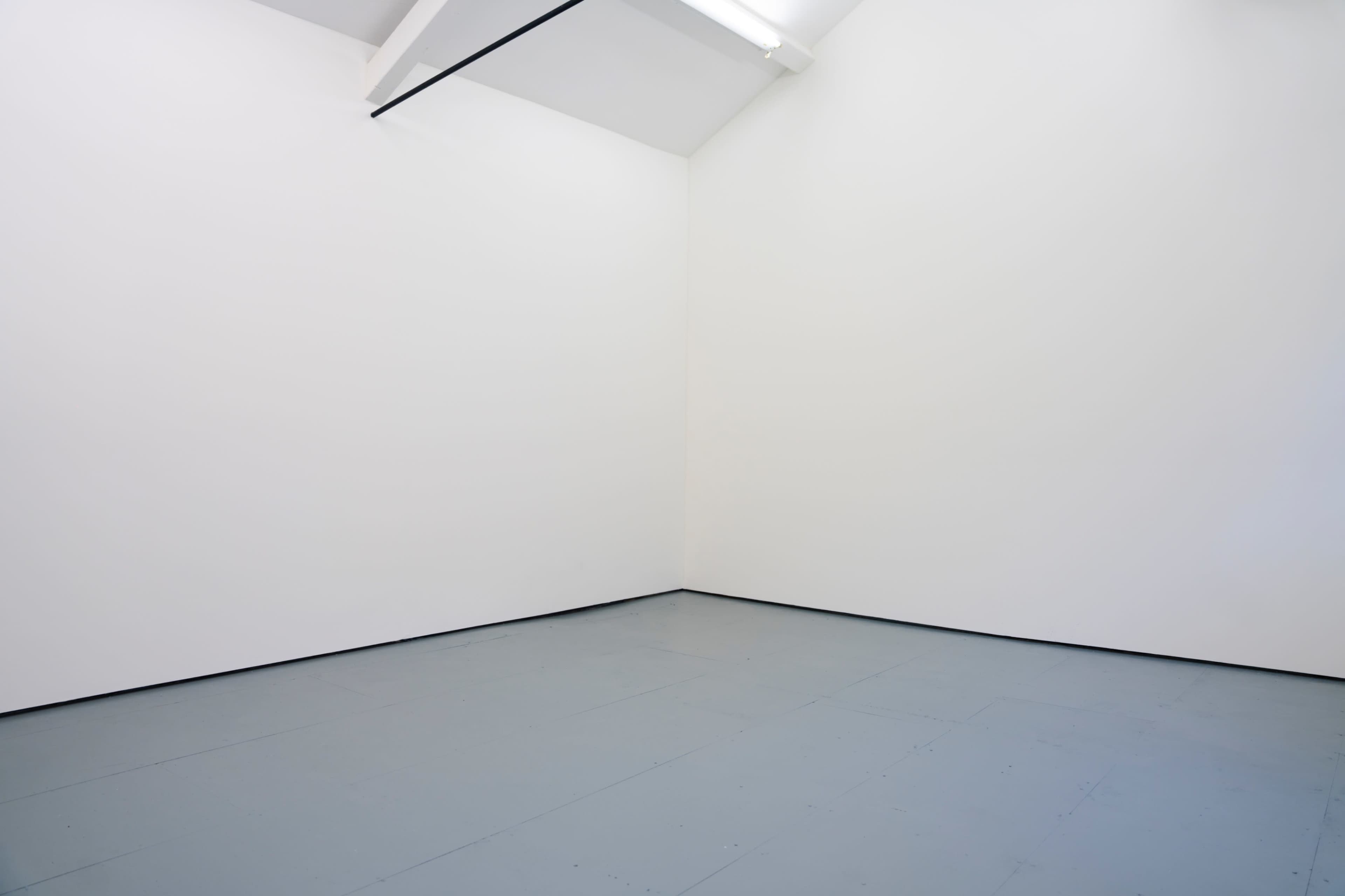 The image shows a minimalist room with clean white walls and a gray floor.