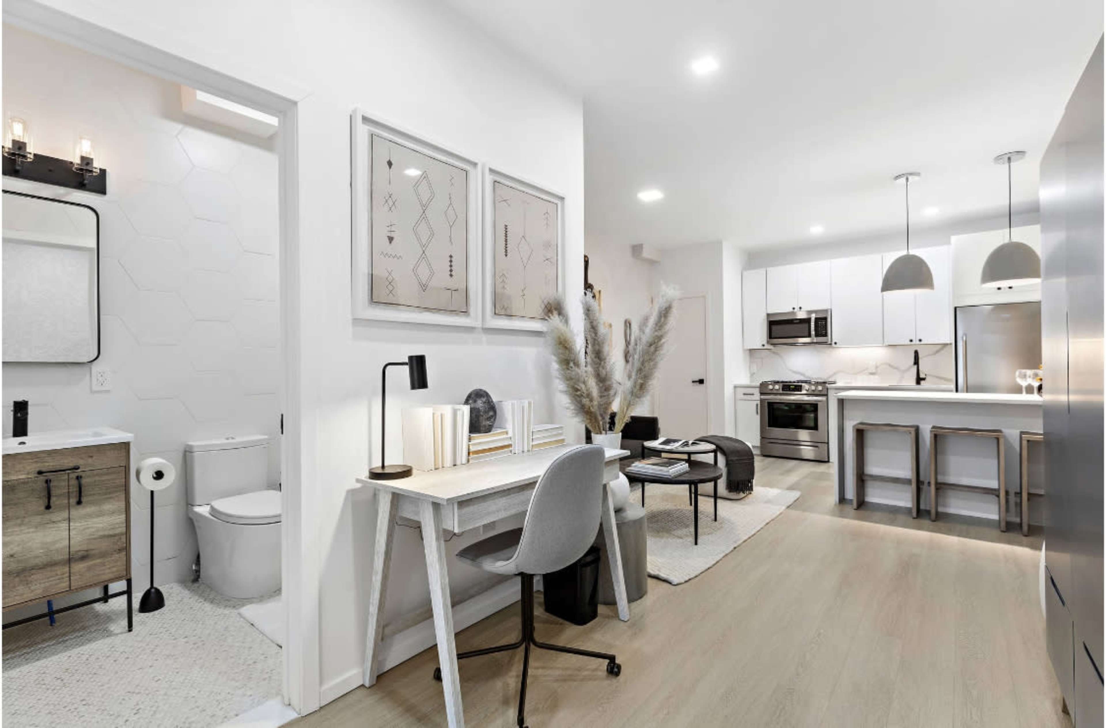 A modern, open-concept living space with a small dining area, kitchen, and a workspace featuring a desk and chair.
