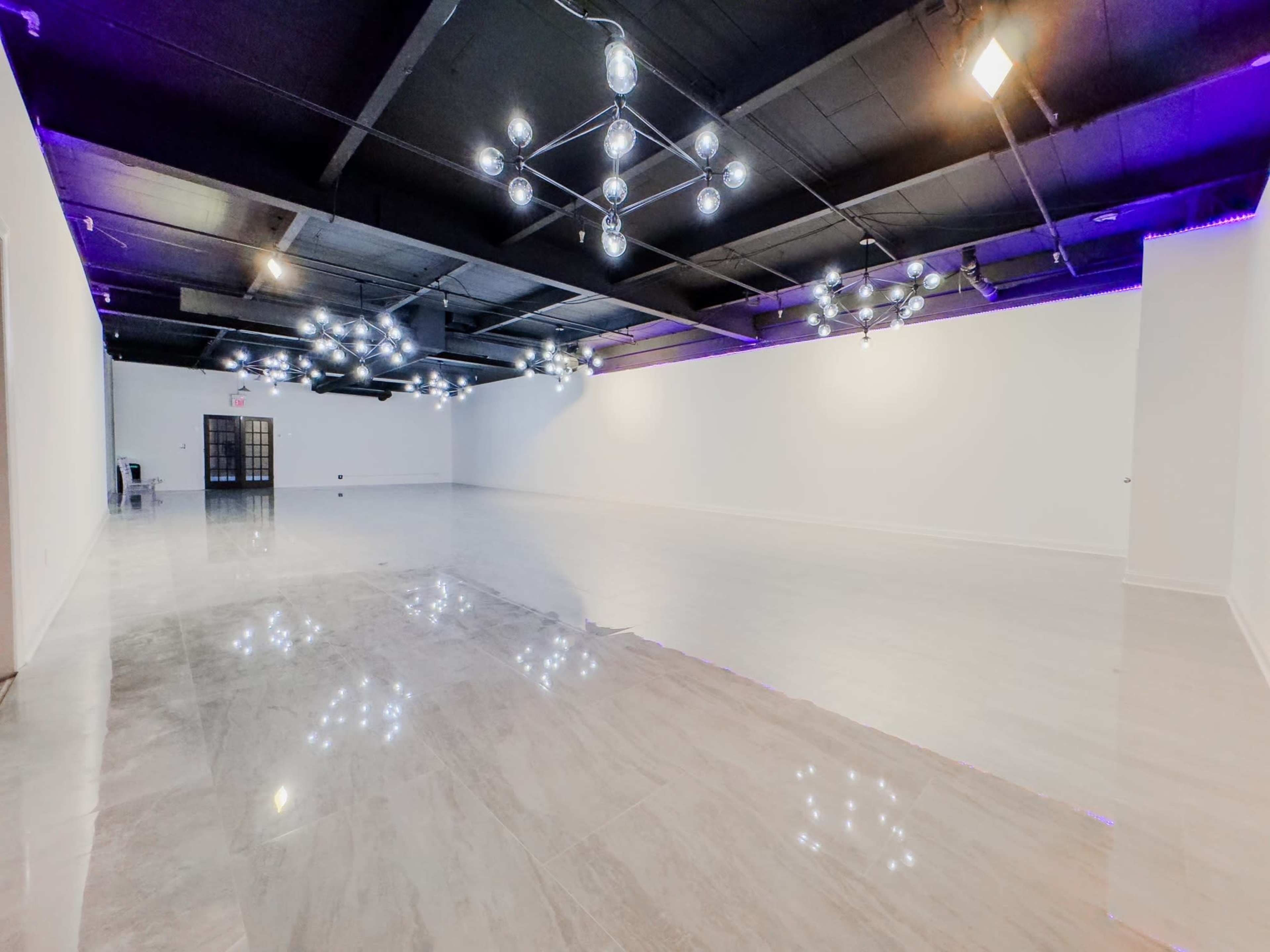 The image shows a spacious, well-lit room with modern lighting fixtures and a polished floor.