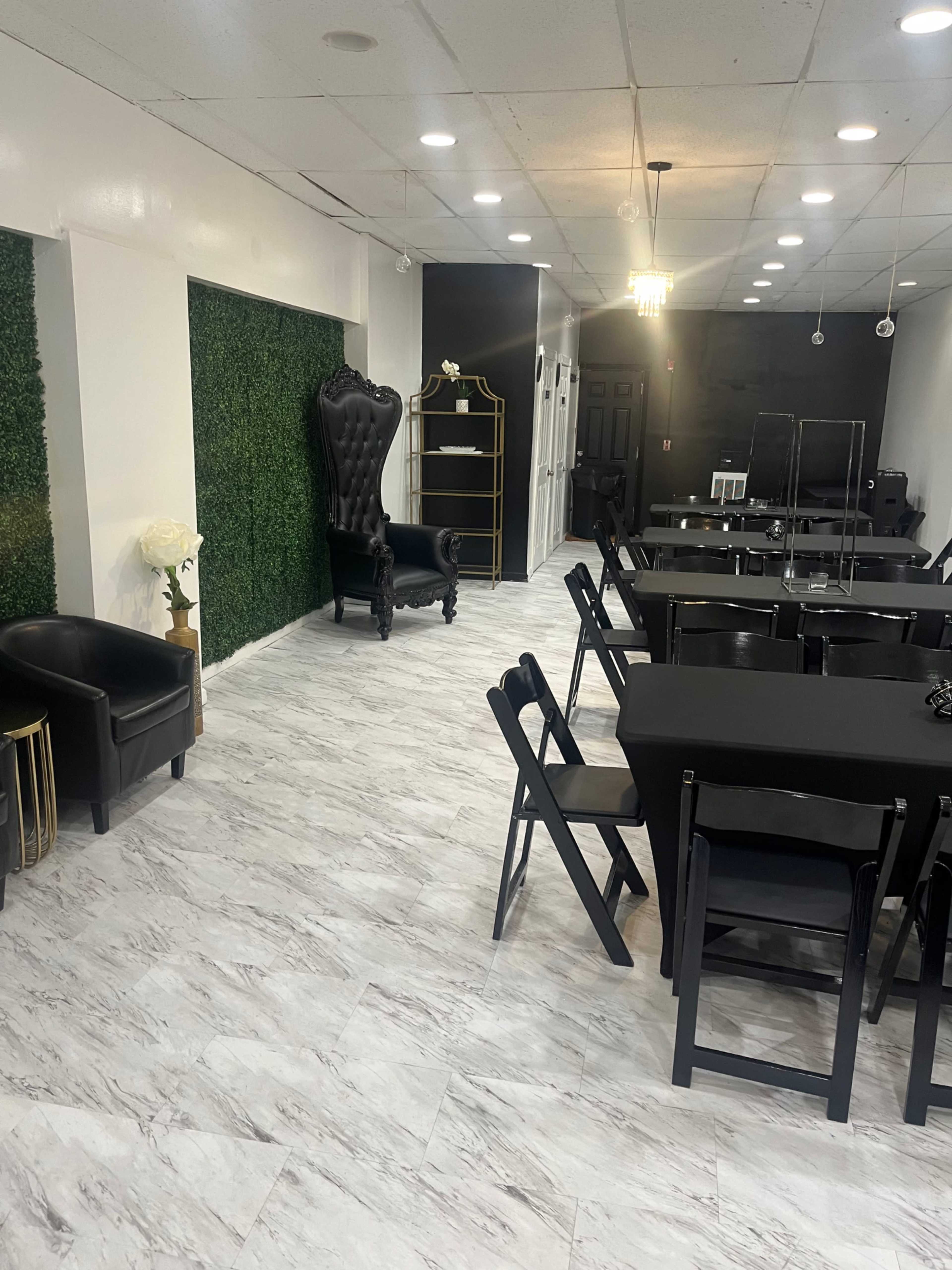 A modern interior space featuring dark furniture, a green wall, and several tables arranged in a classroom or event layout.
