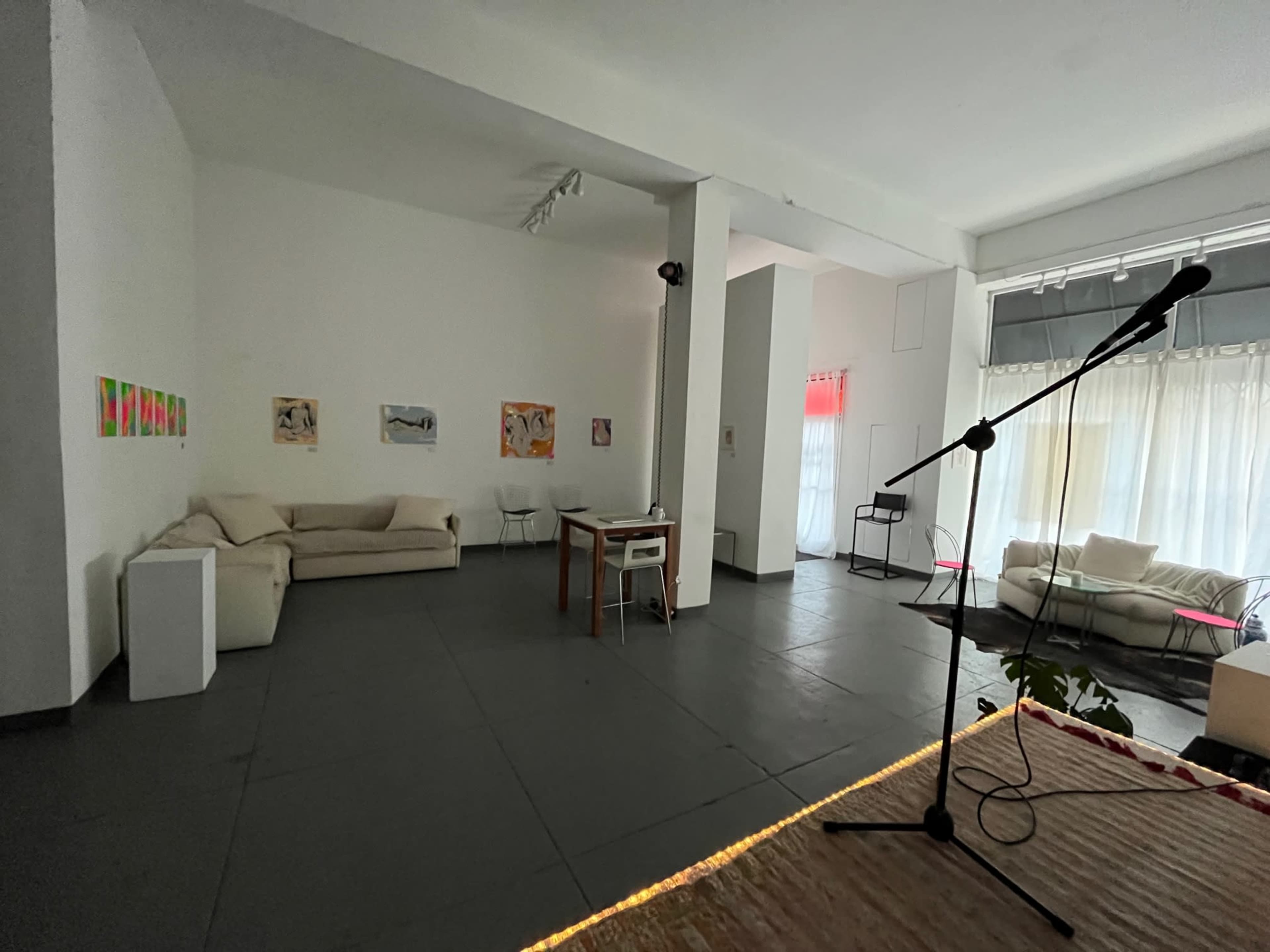 A spacious, minimalist room with white walls, a sofa, a table with chairs, and artwork displayed on the walls.