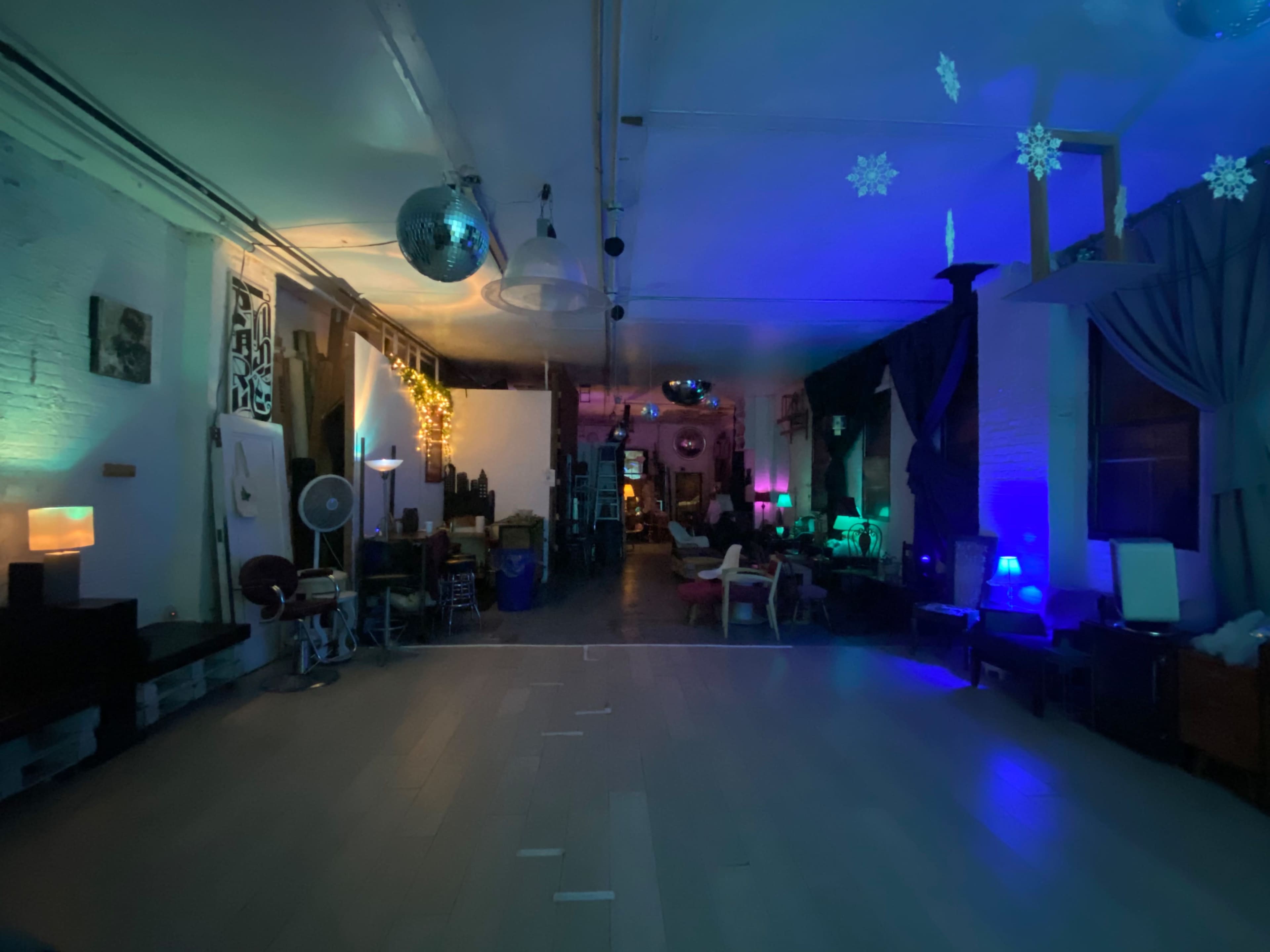 A spacious room with various seating arrangements and colorful lighting effects, including lamps and disco balls.