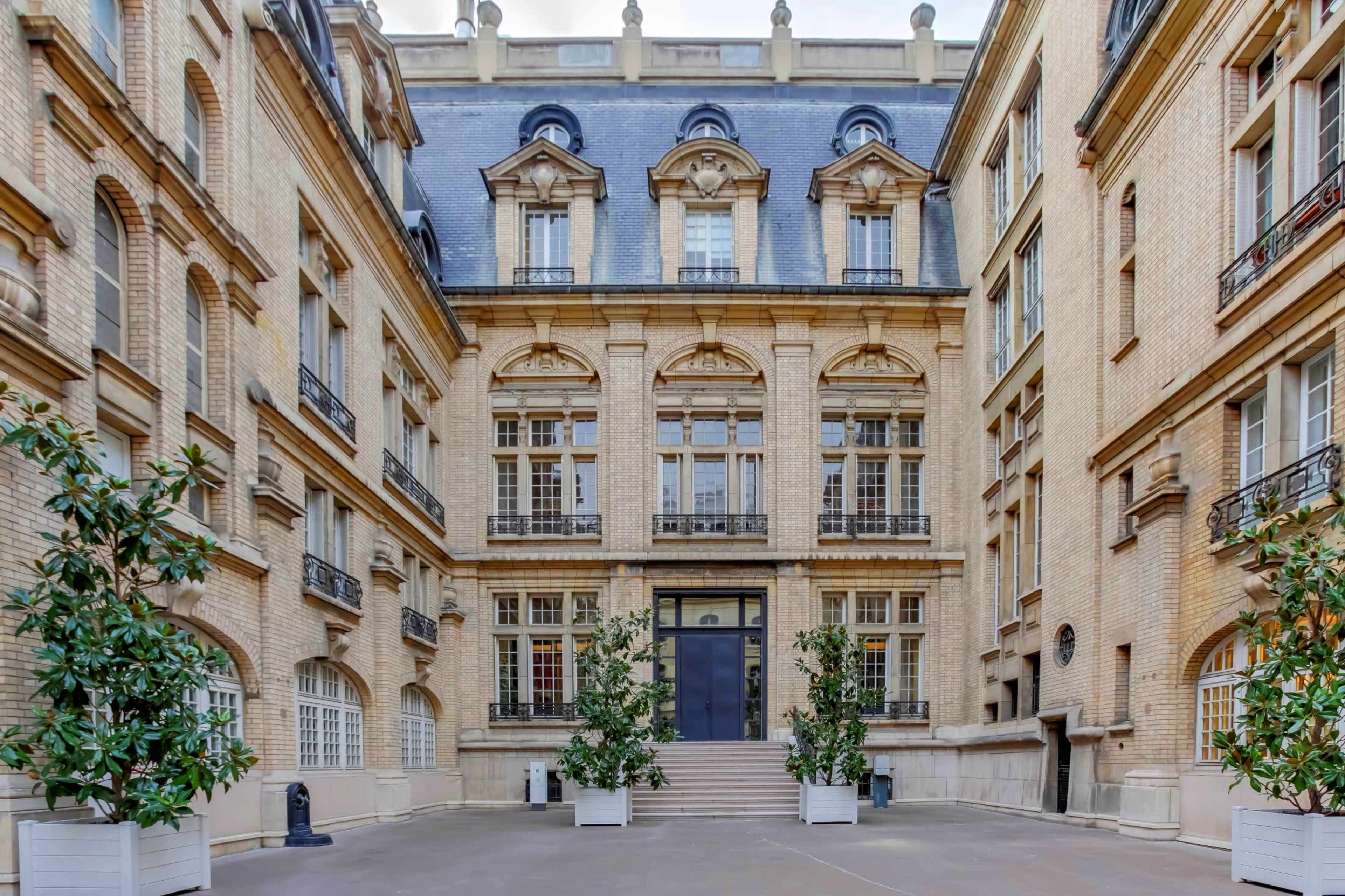 A stately brick building with an ornate facade and symmetrical windows surrounding a central courtyard.