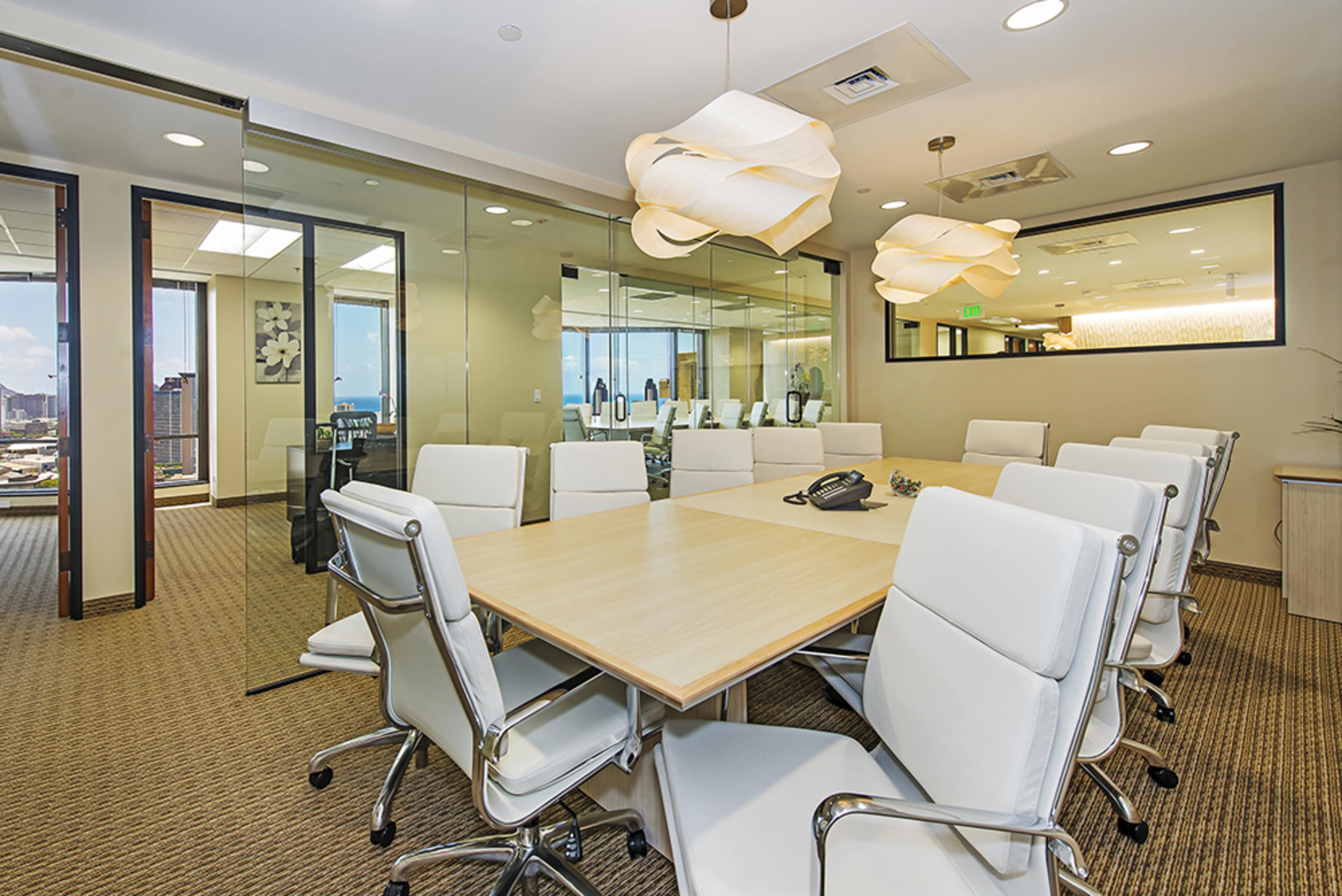 A modern conference room features a long wooden table surrounded by white ergonomic chairs, with glass walls offering views of a city skyline.