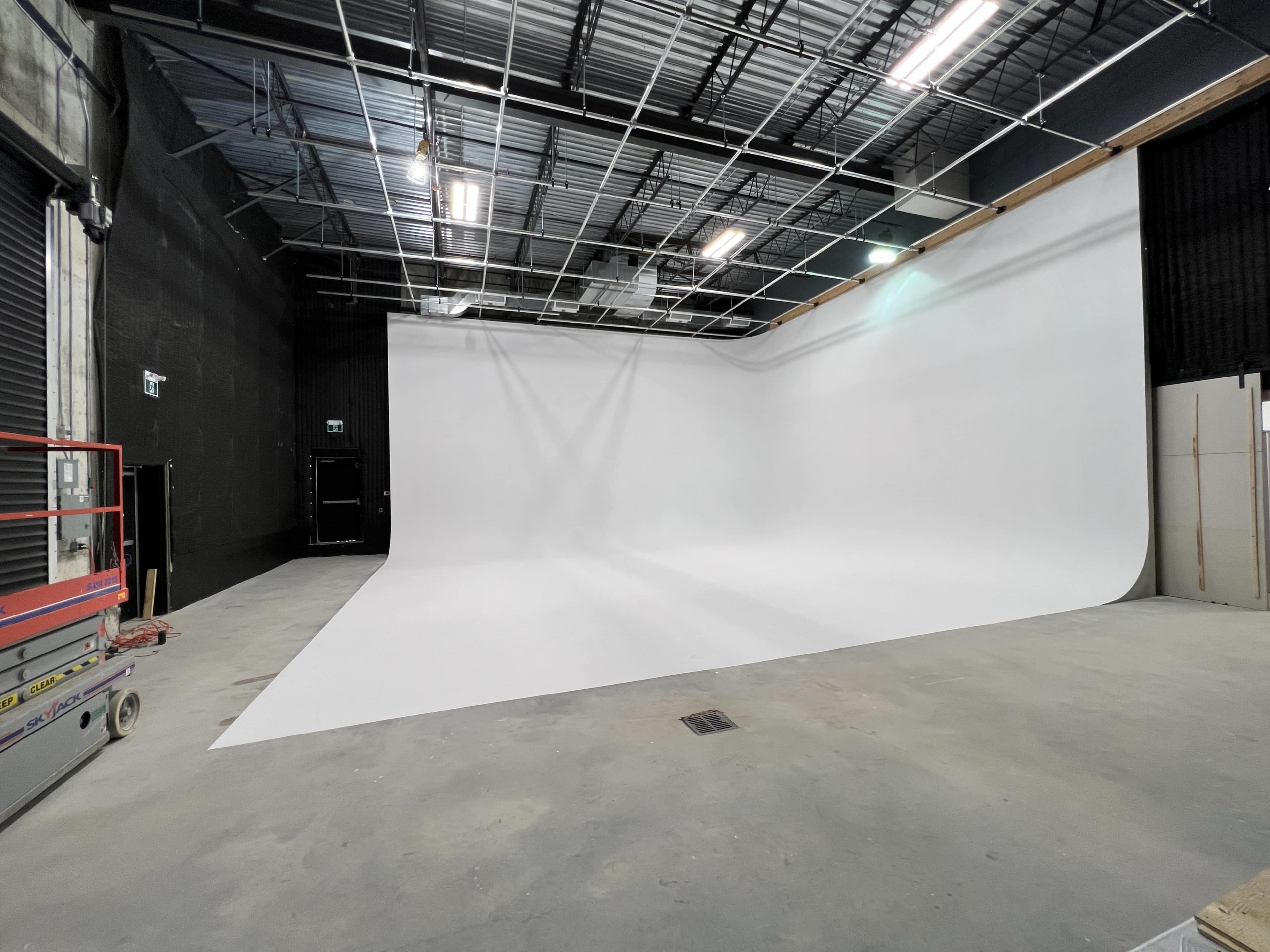A spacious photo studio with a seamless white backdrop and a concrete floor.