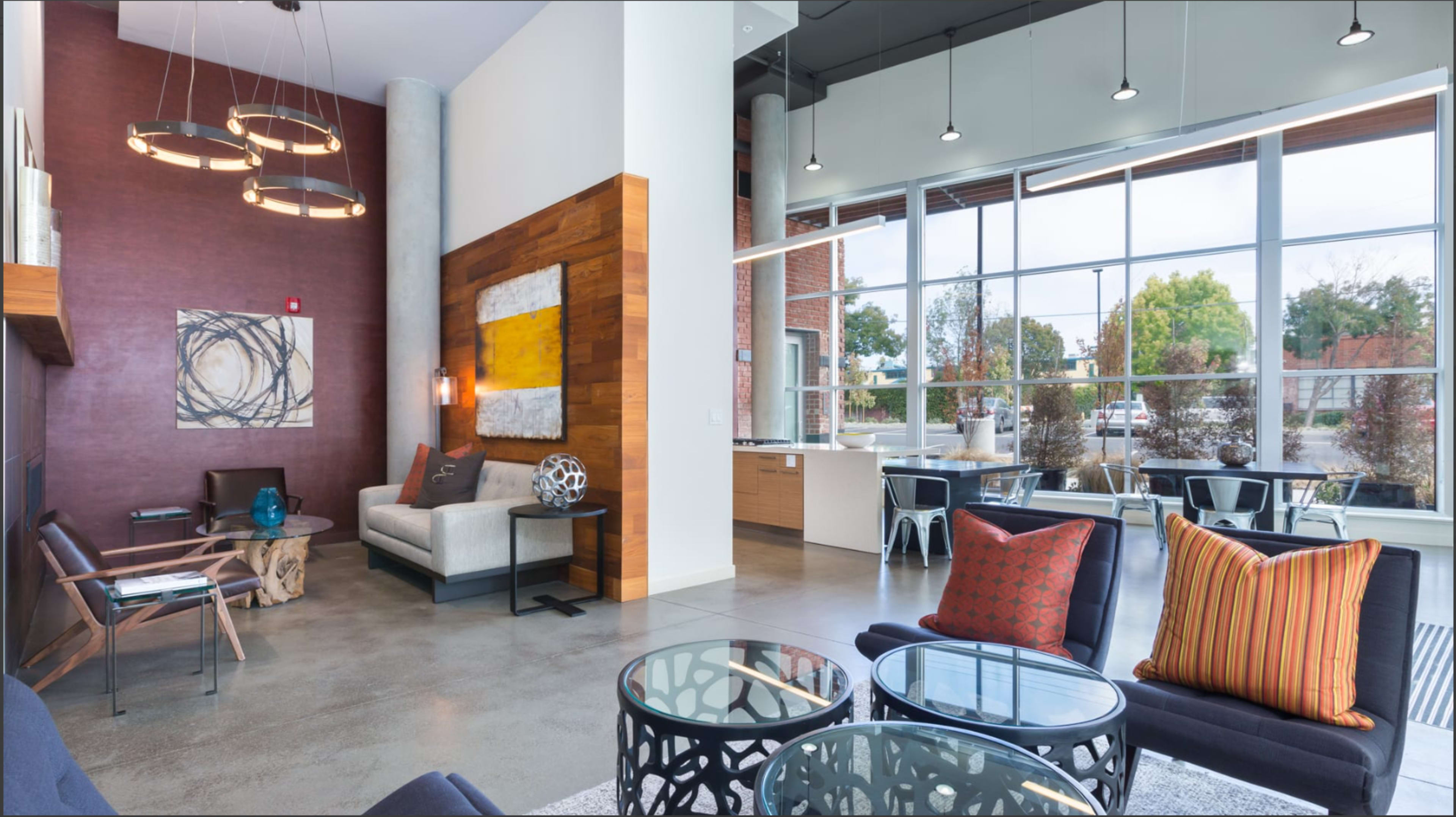 A modern lounge area with seating arrangements, large windows, and contemporary decor.