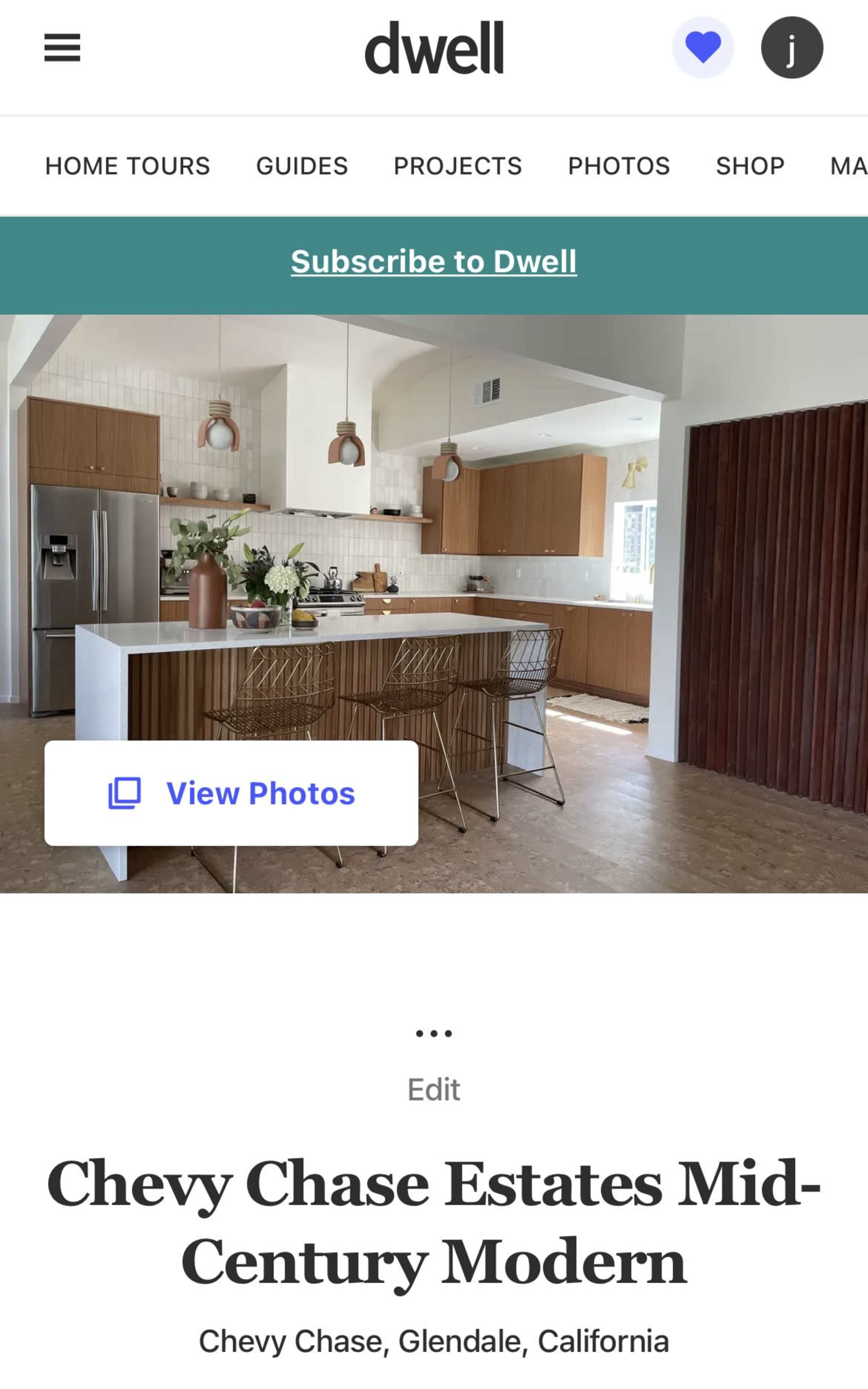 A modern kitchen with wooden cabinetry, a large island, and pendant lighting in a light-filled space.