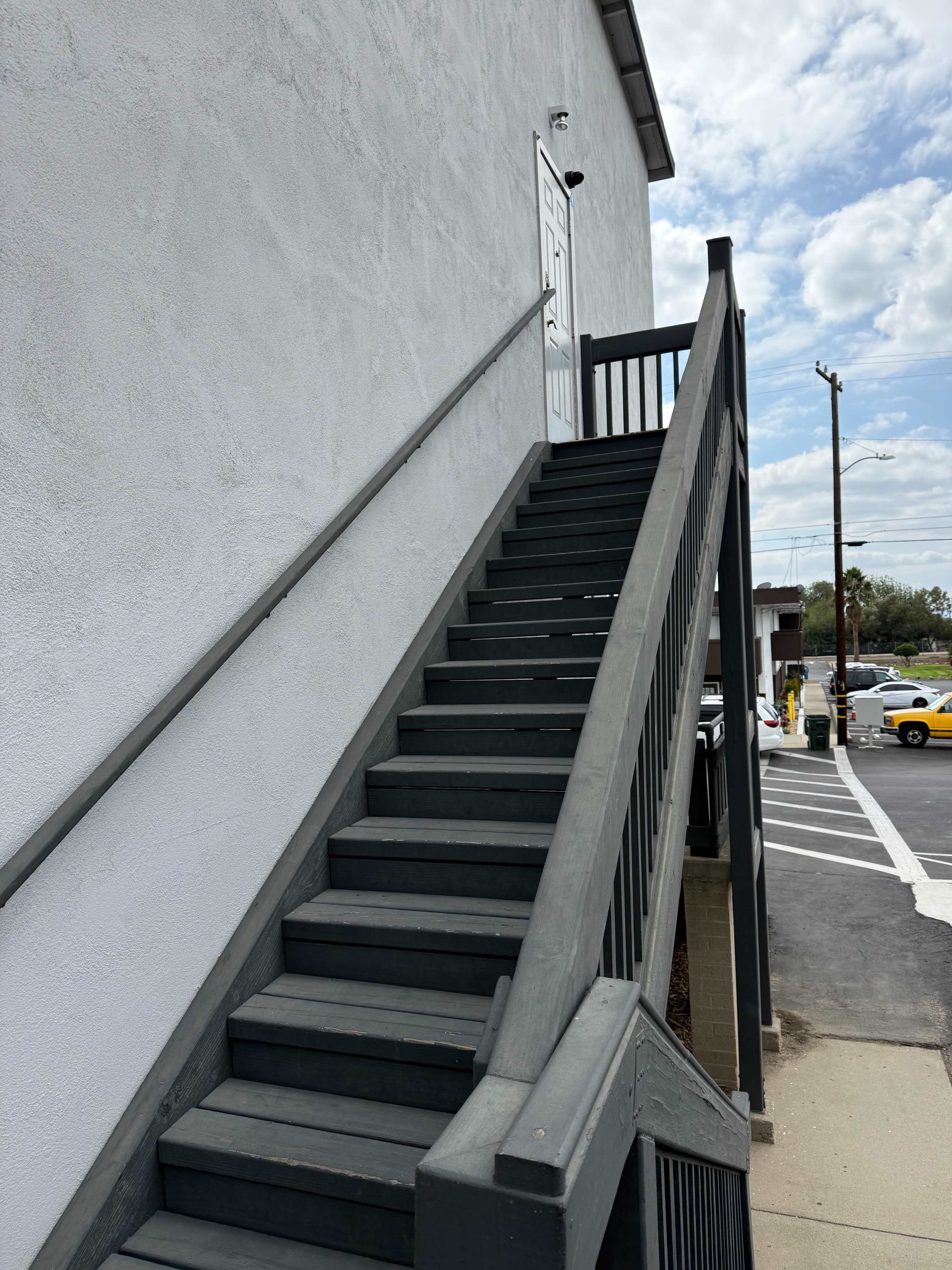 The image shows a set of wooden stairs leading up to a door on the side of a building.