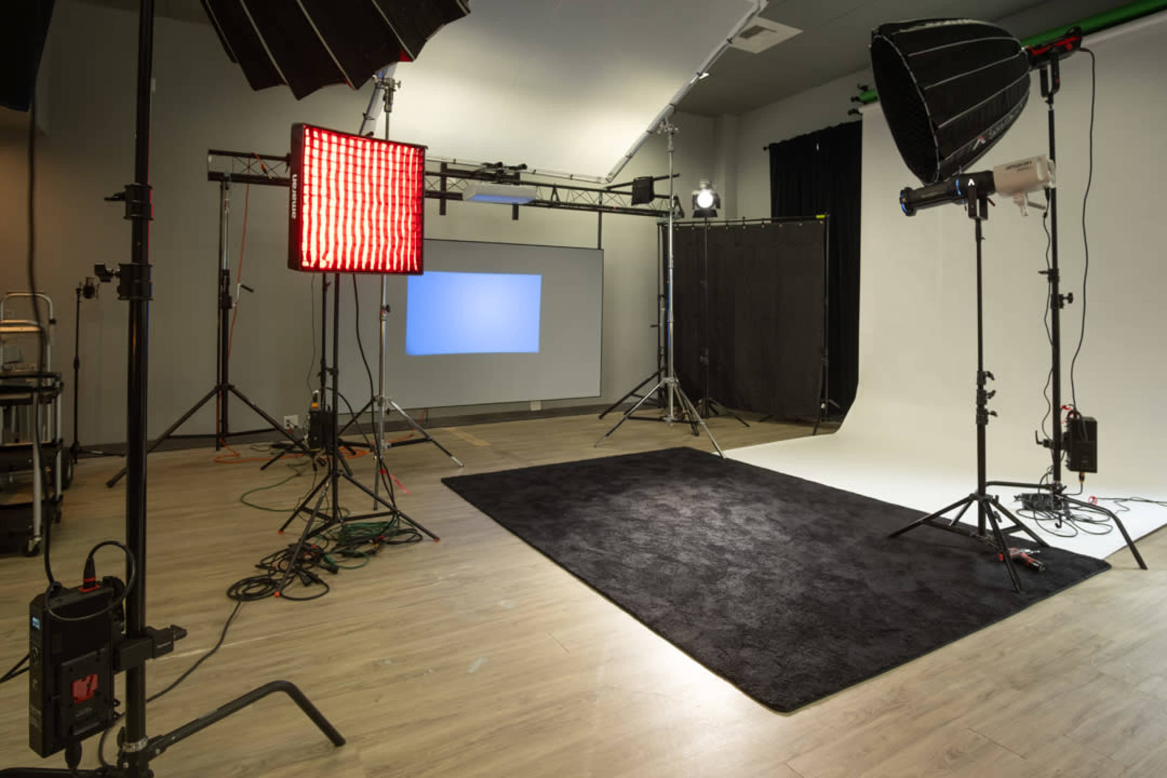 The image depicts a photography studio equipped with multiple lighting setups and a backdrop ready for a photoshoot.