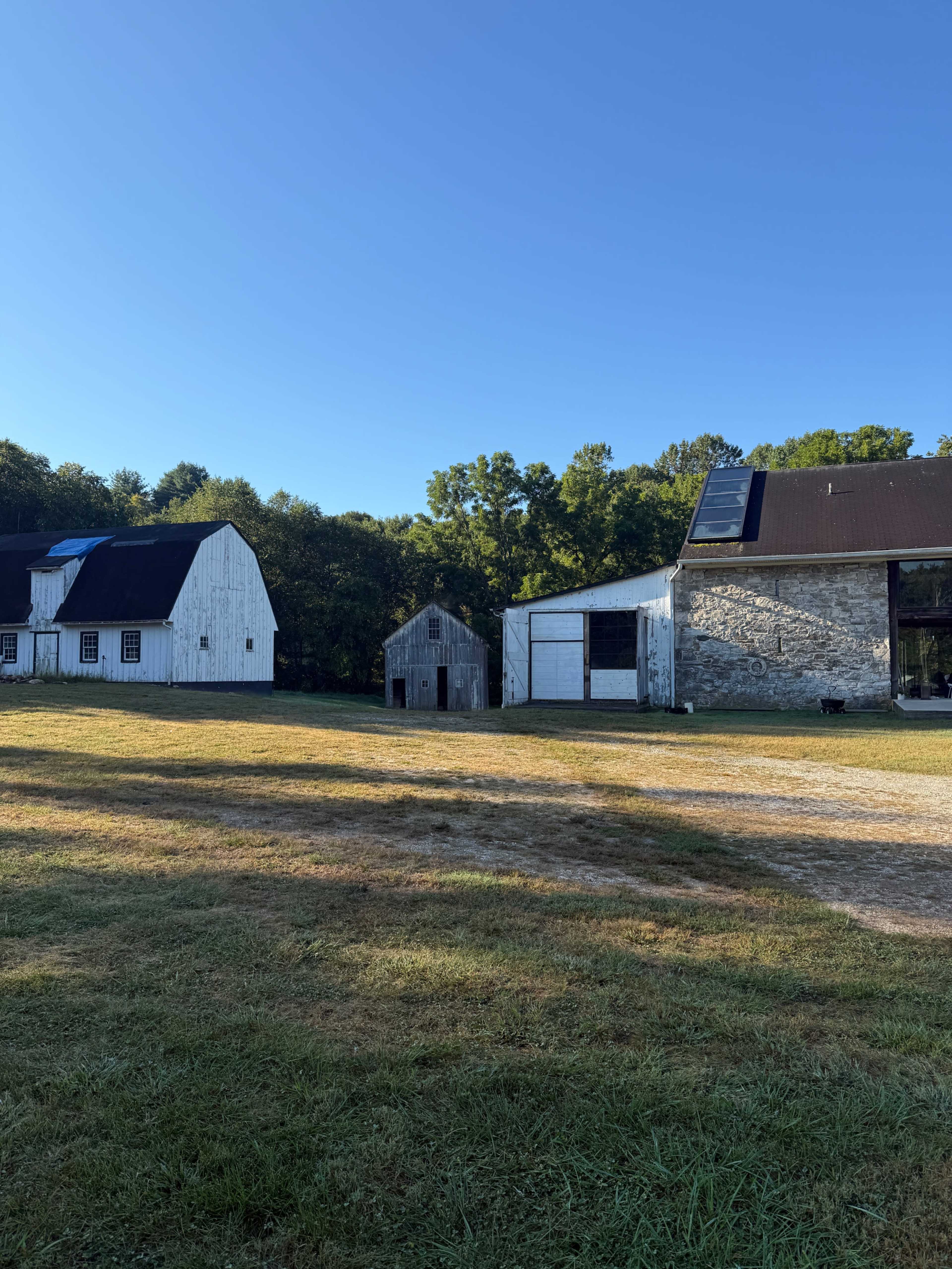 The image shows a rural landscape with several barns and outbuildings under a clear blue sky.