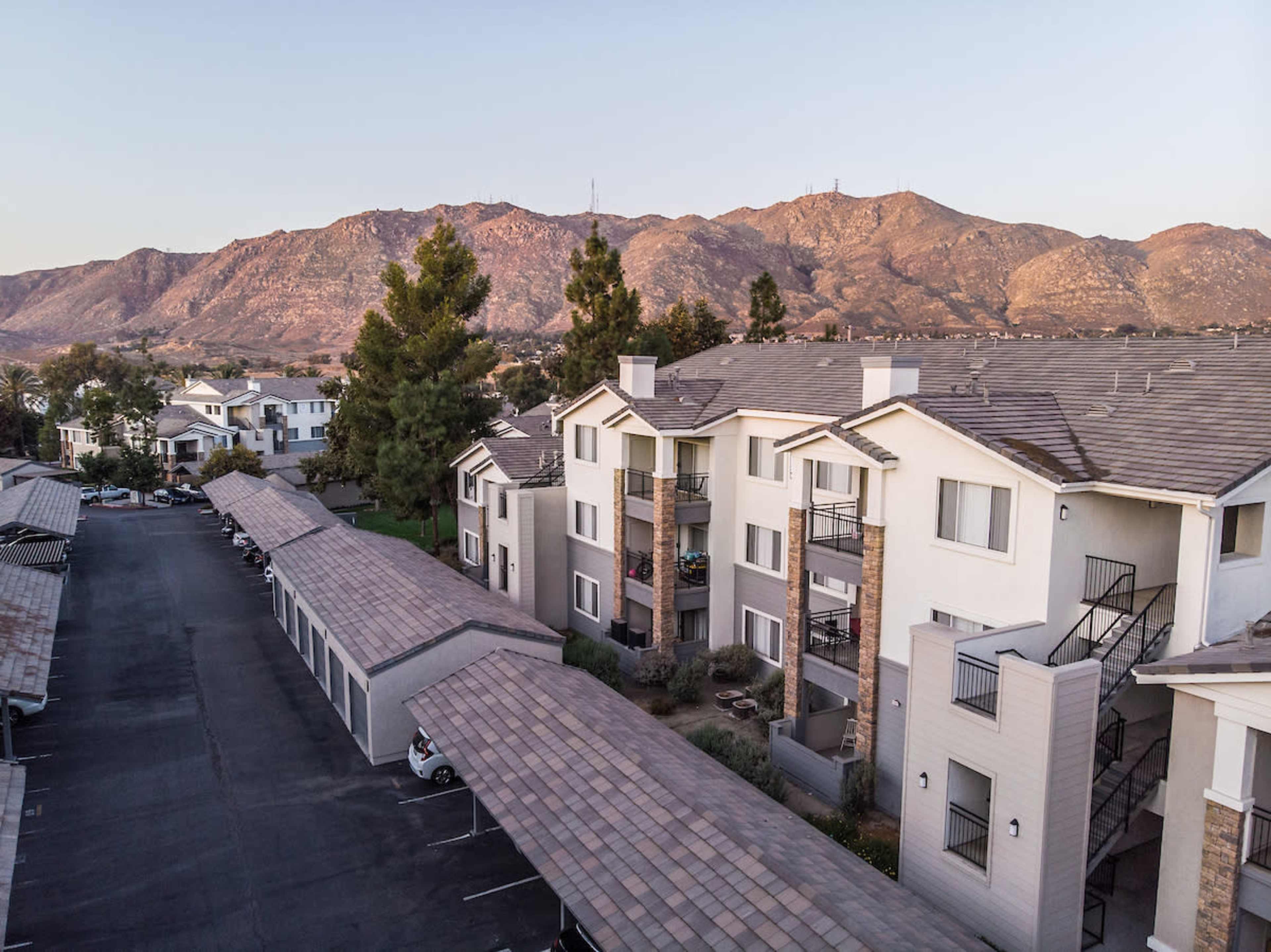A residential apartment complex situated near a mountain range during sunset.
