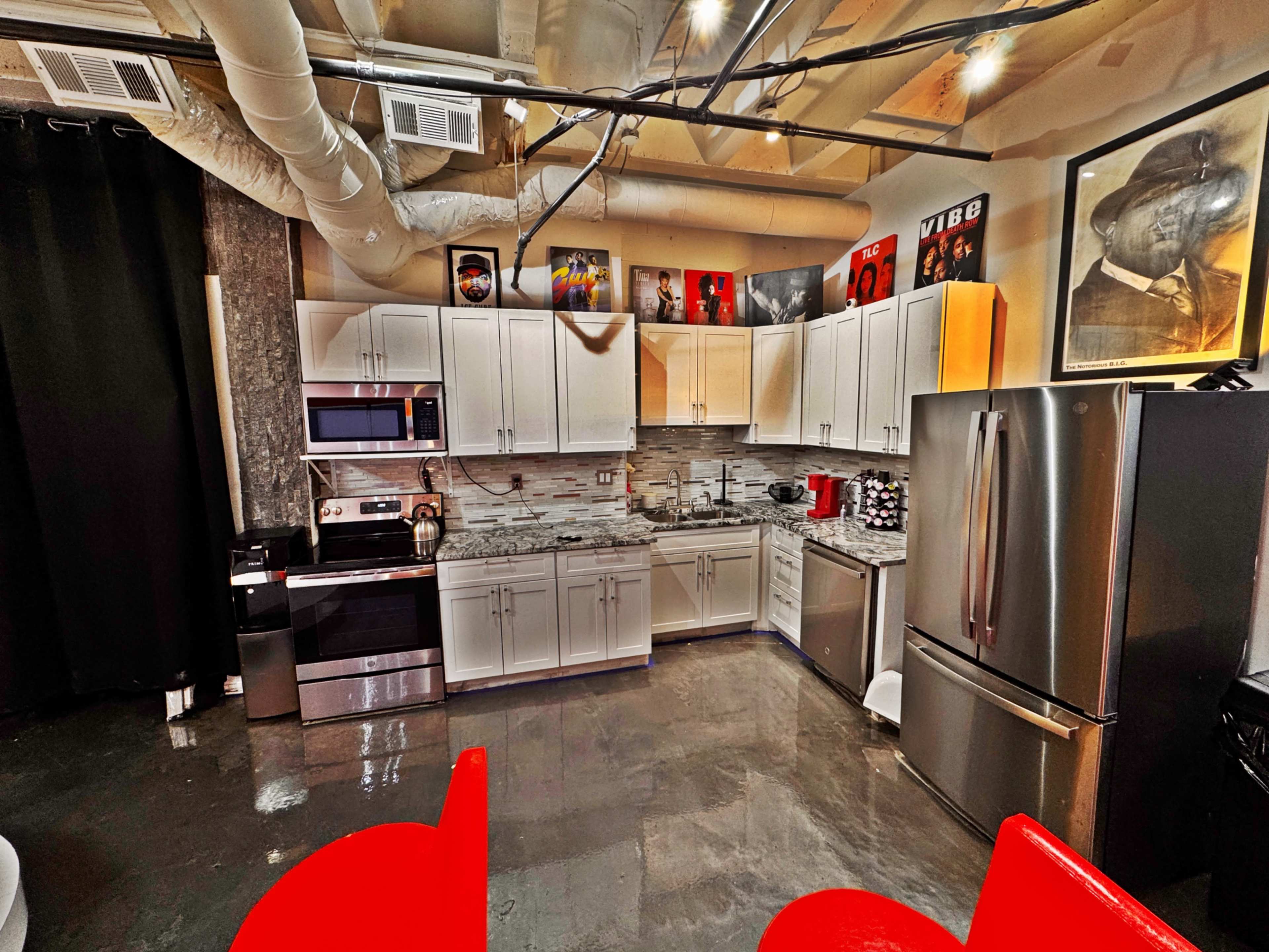 A modern kitchen features stainless steel appliances, gray cabinets, and decorative wall art.