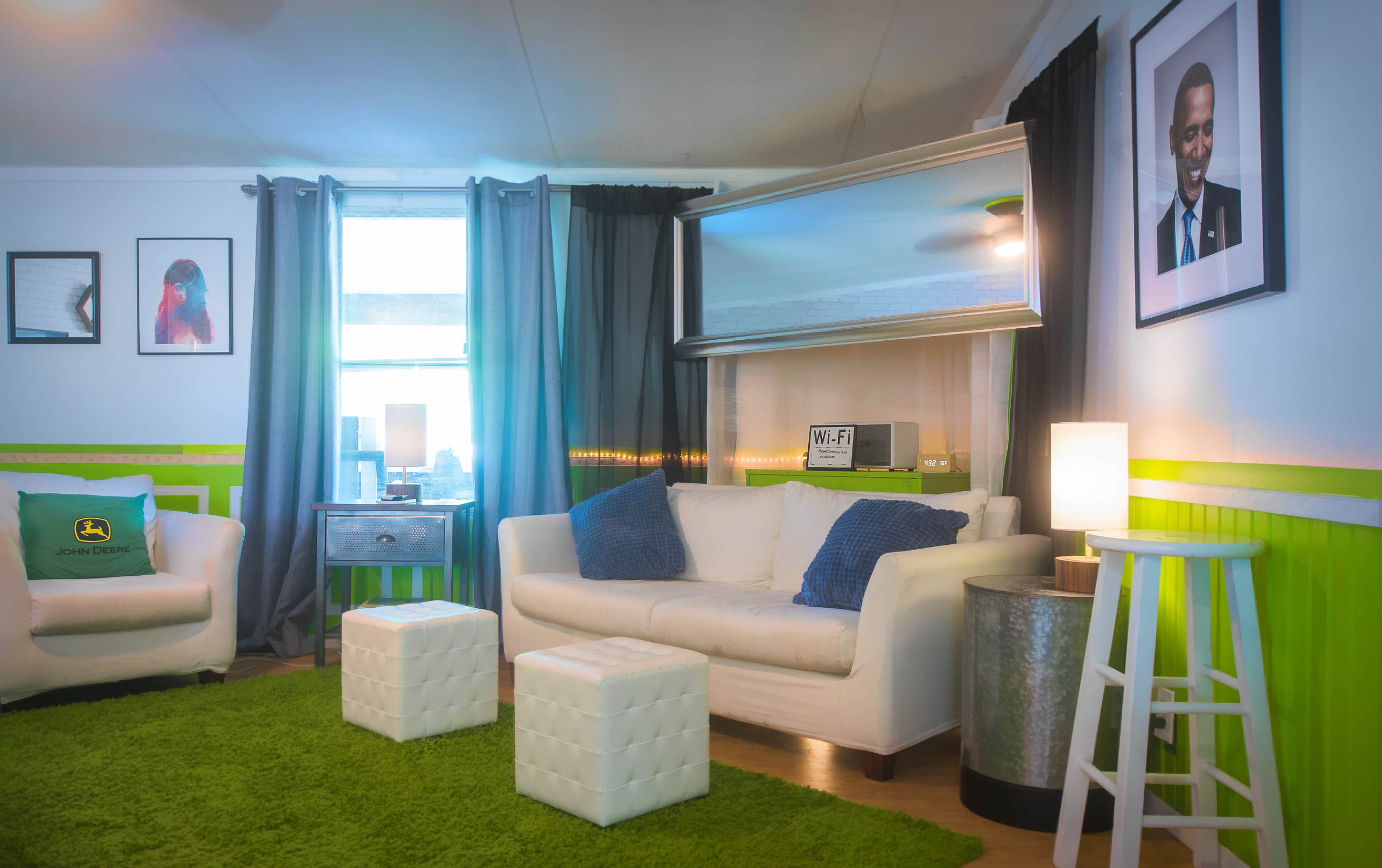 A cozy living room with a white sofa, green carpet, and modern decor including a mirror and framed art.