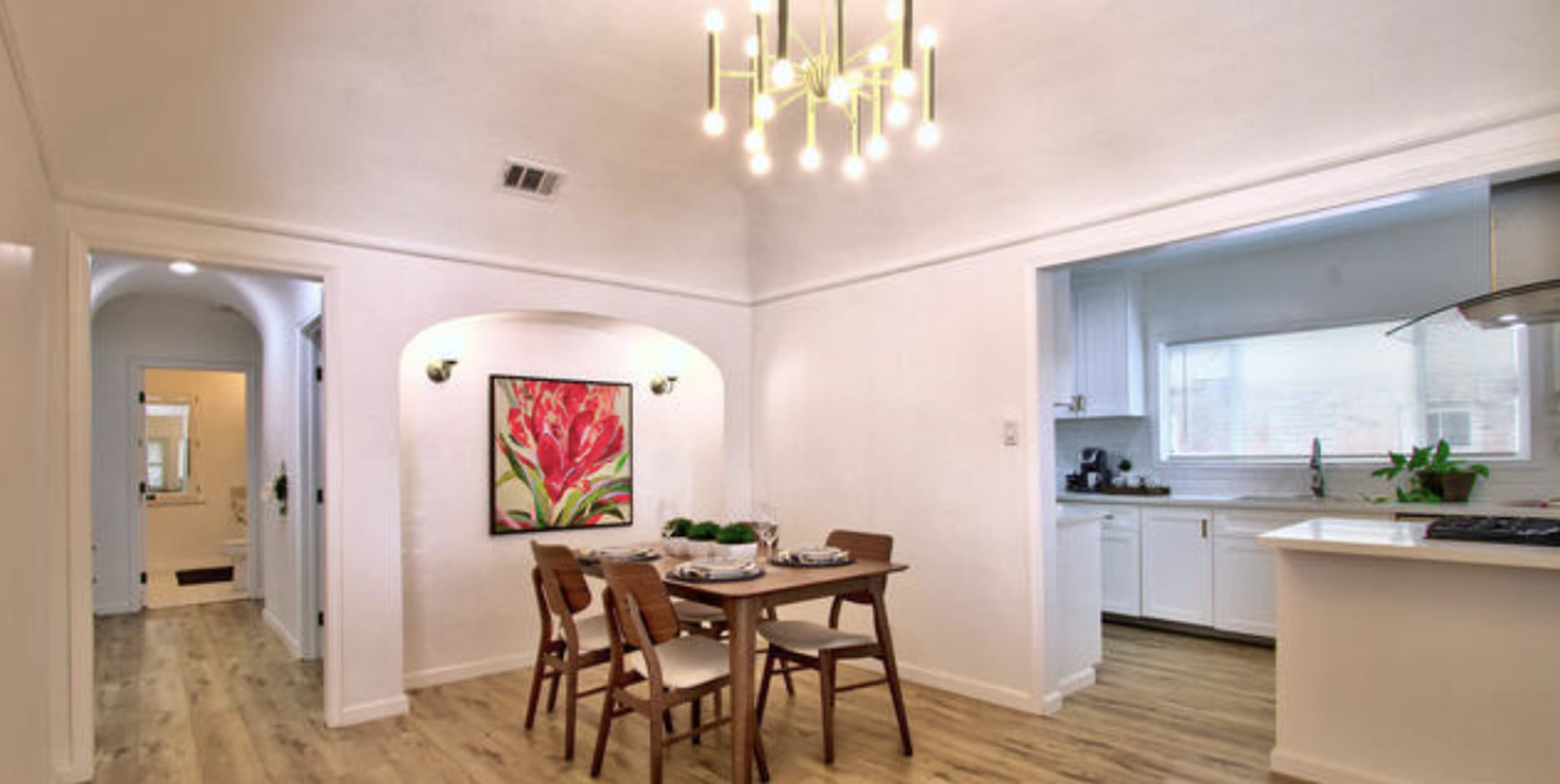 A dining area with a small table and chairs is connected to a bright kitchen in a modern home.