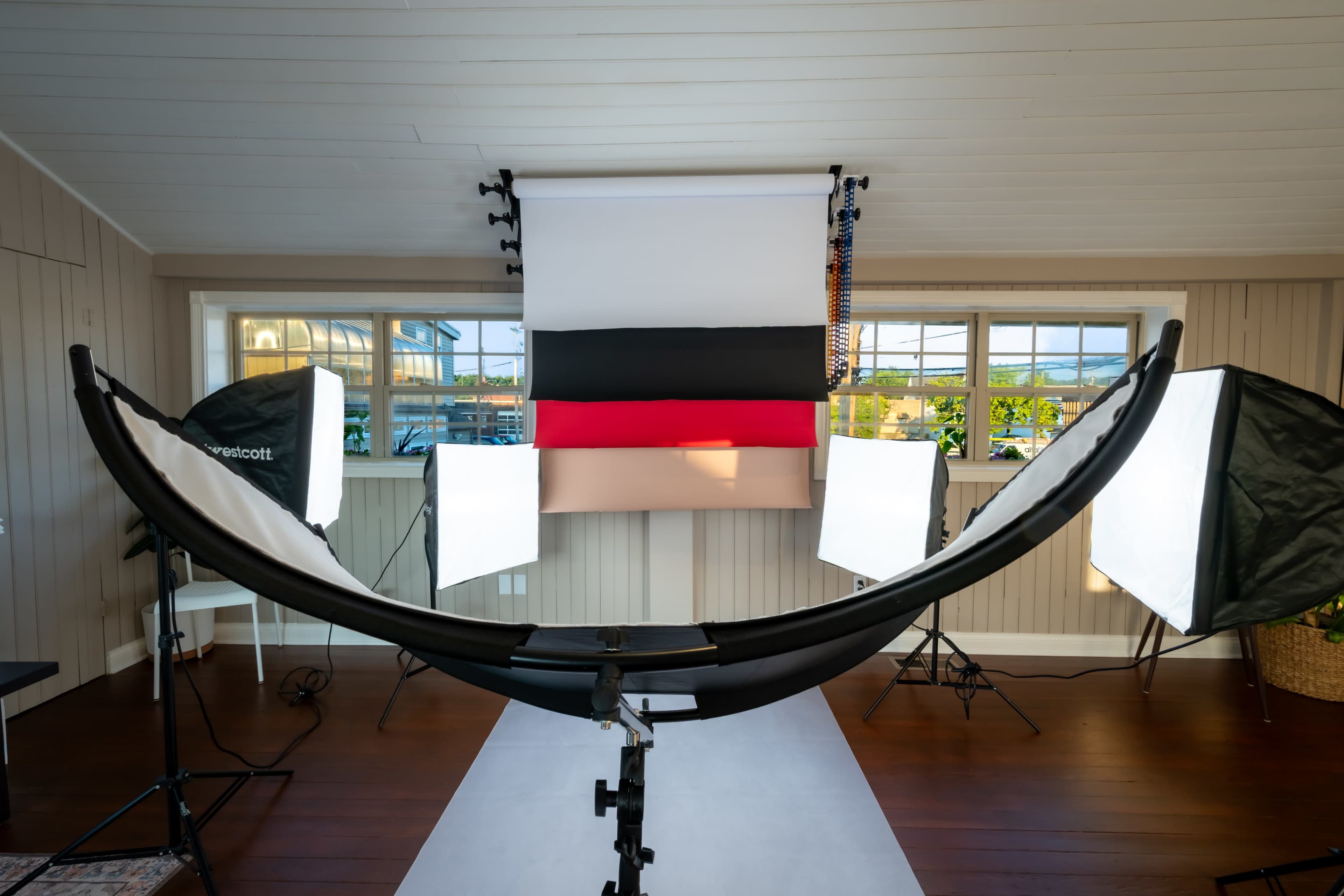 A photography studio is set up with a curved backdrop and multiple light sources arranged around it.