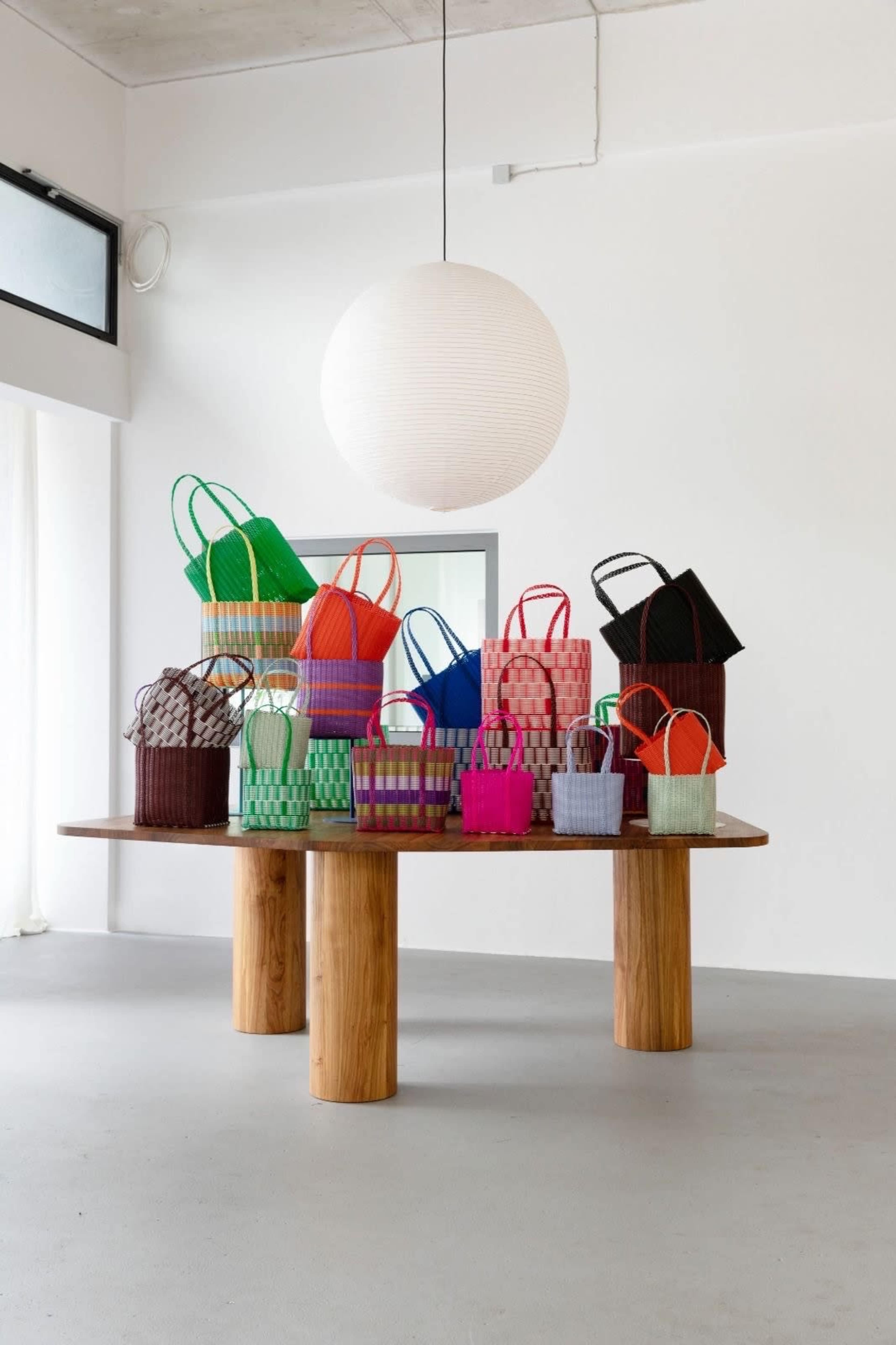 A wooden table displays an assortment of colorful woven baskets in various sizes and shapes.