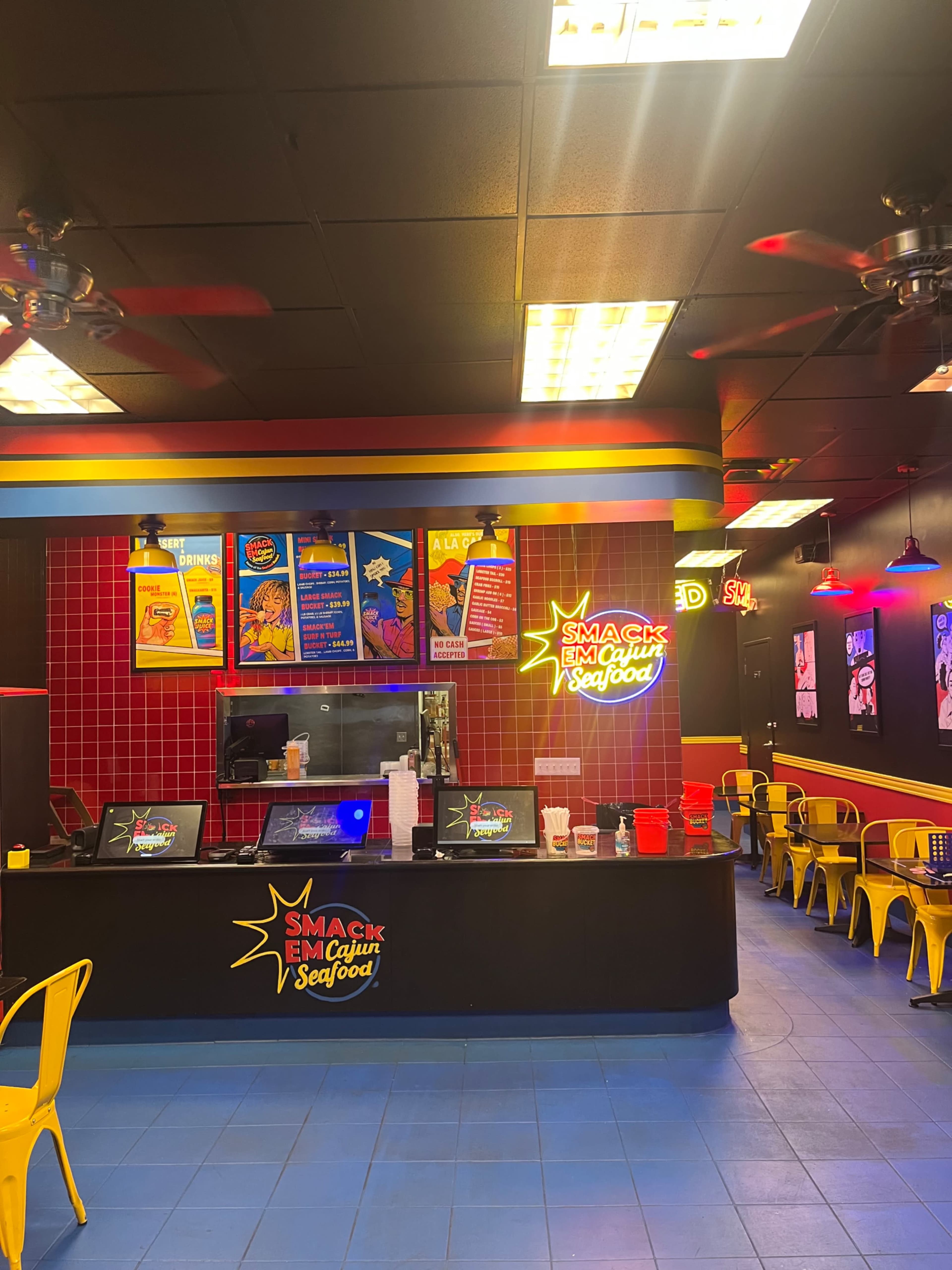The image shows a brightly colored seafood restaurant interior with a counter, seating area, and vibrant decorations featuring neon signs.