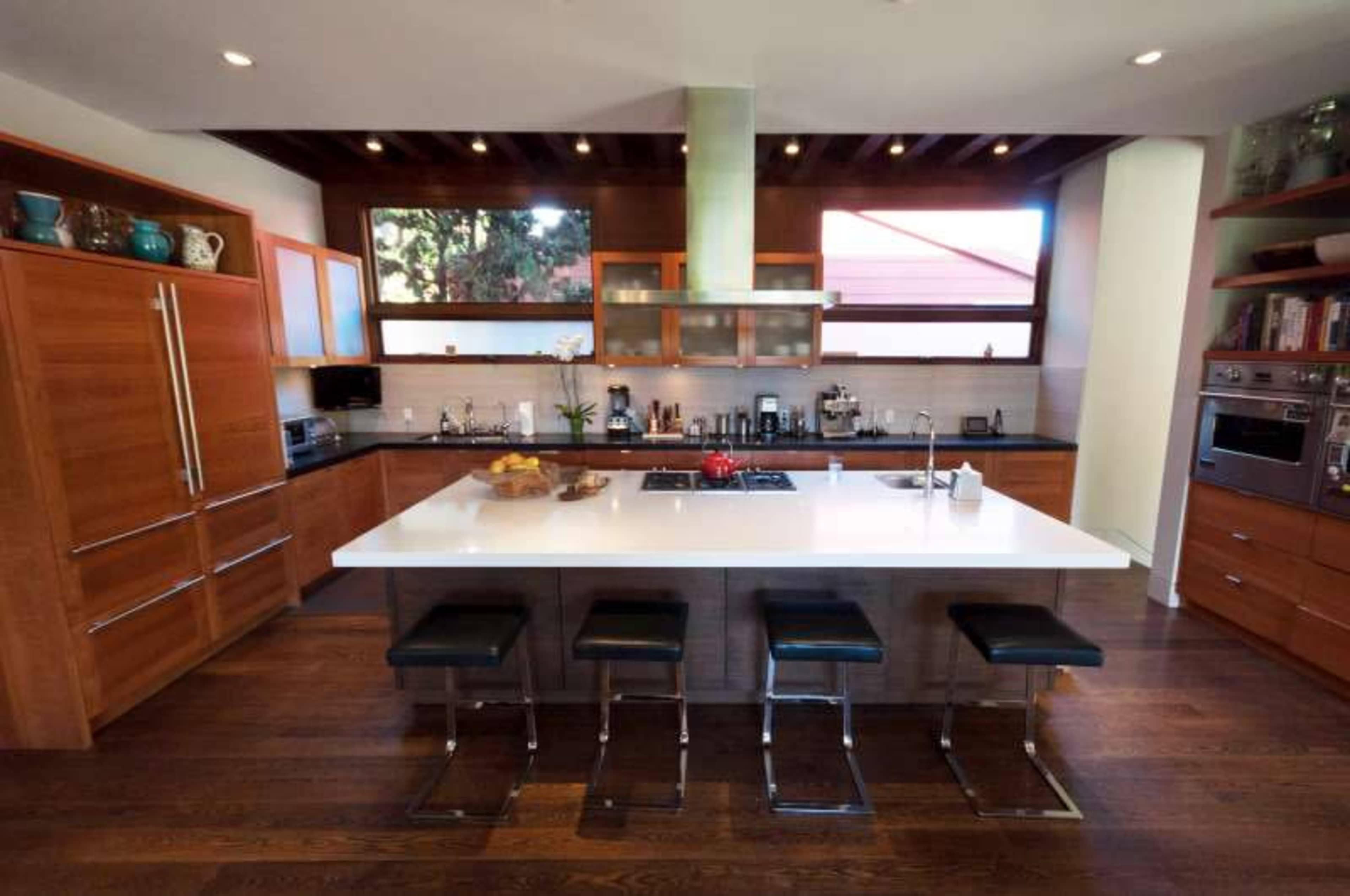 A modern kitchen features wooden cabinets, a large island with seating, and stainless steel appliances.