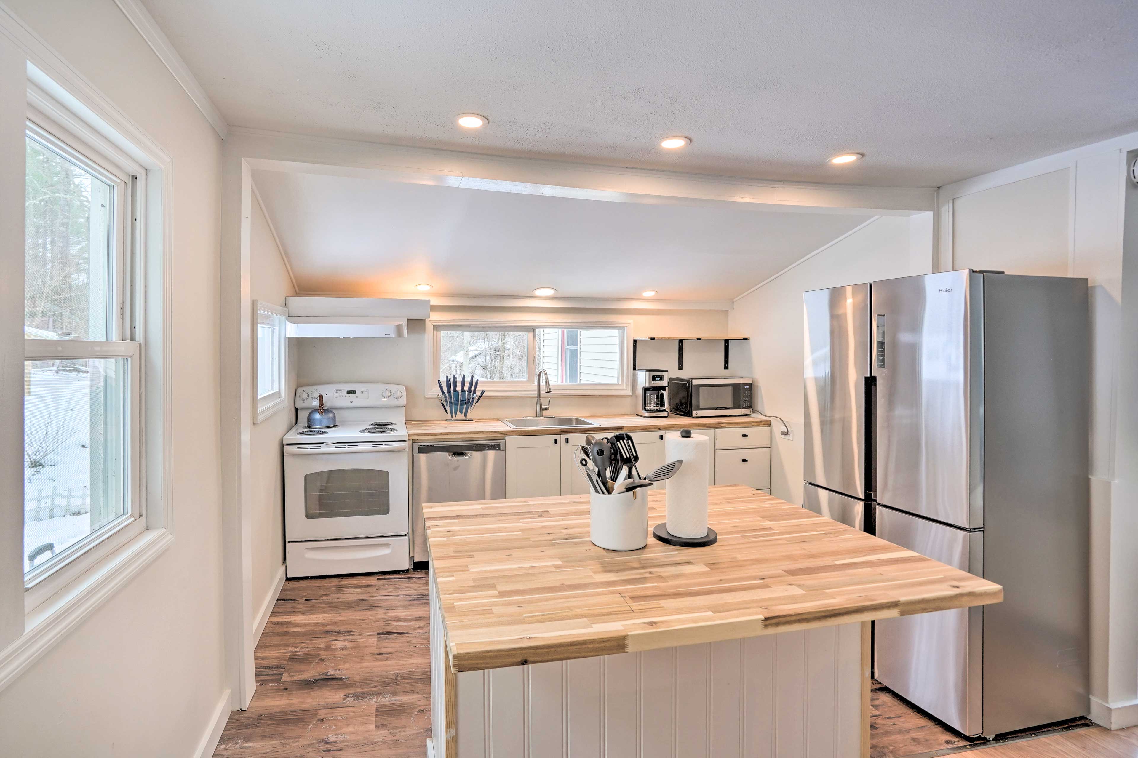 A kitchen features a central wooden island, stainless steel appliances, and ample natural light from multiple windows.