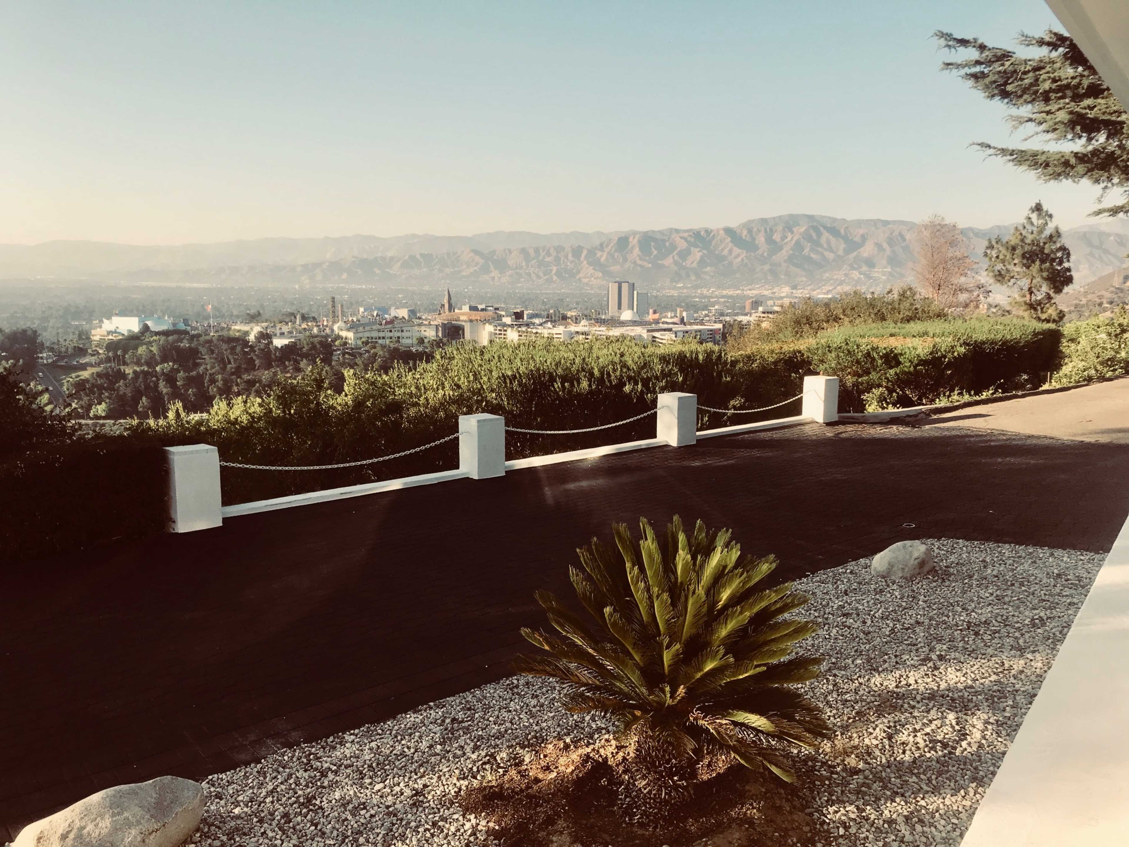 A landscaped terrace overlooks a cityscape and mountains in the distance.
