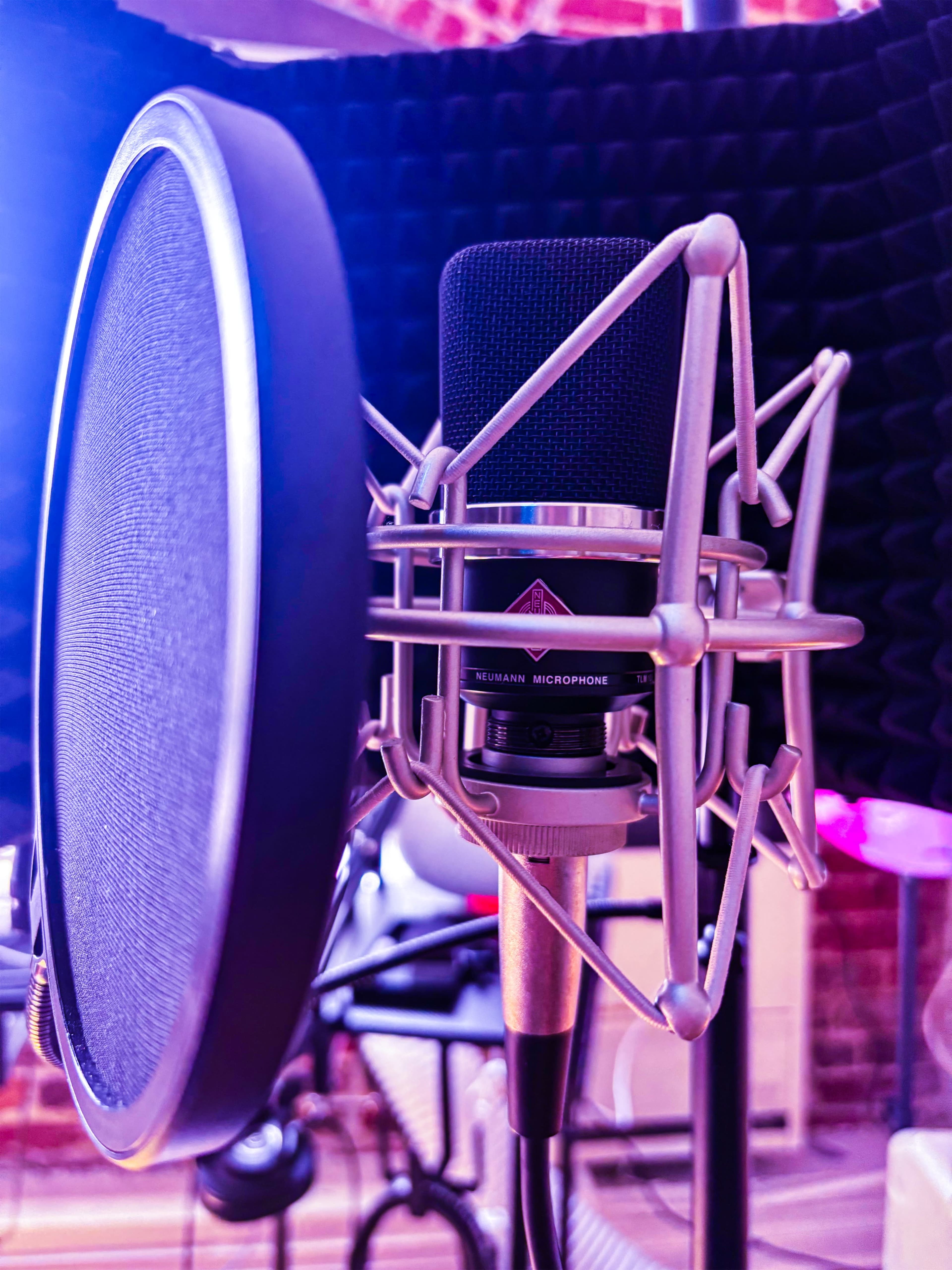 A close-up of a microphone with a pop filter in a recording studio setting.