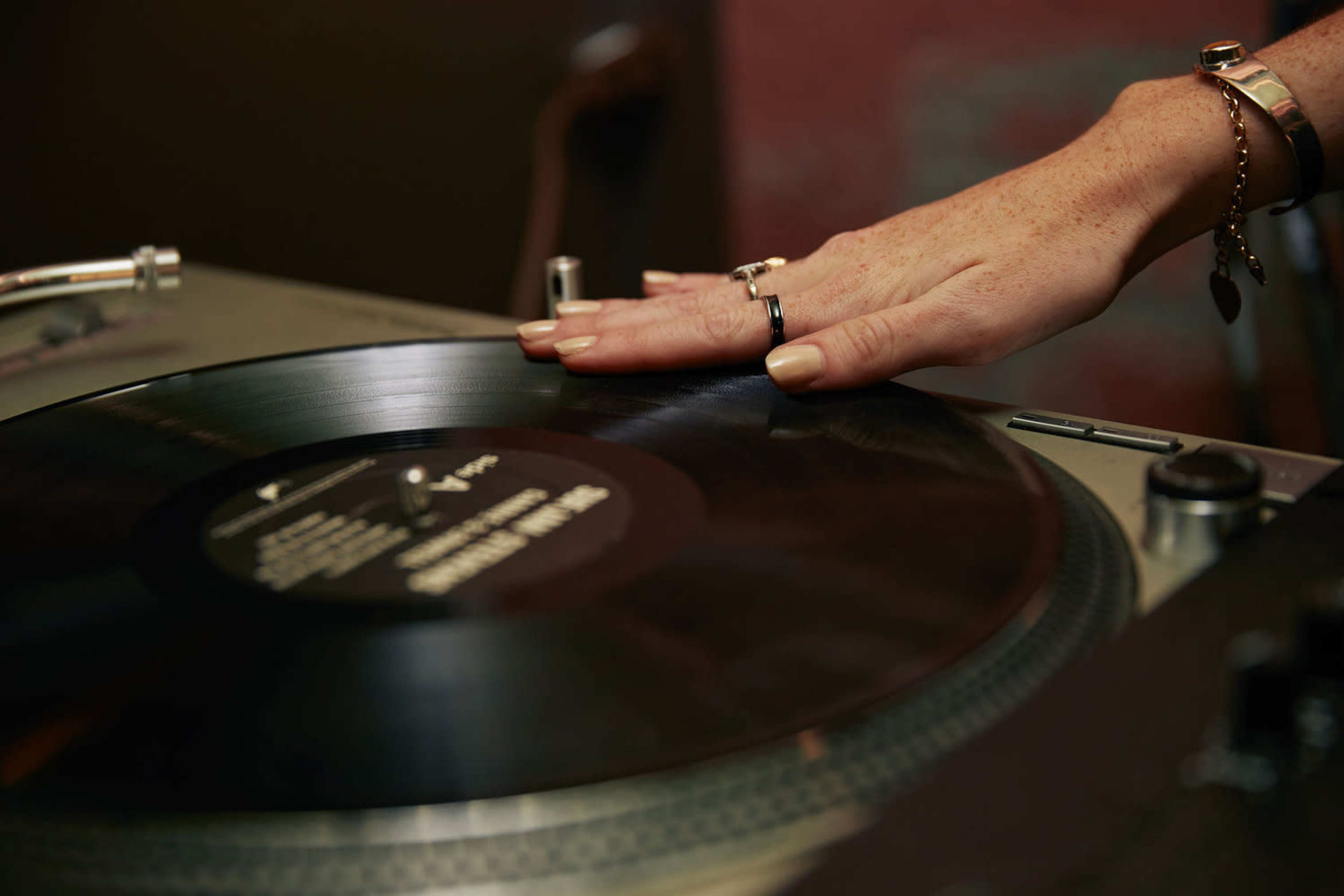 A hand is adjusting a spinning vinyl record on a turntable.
