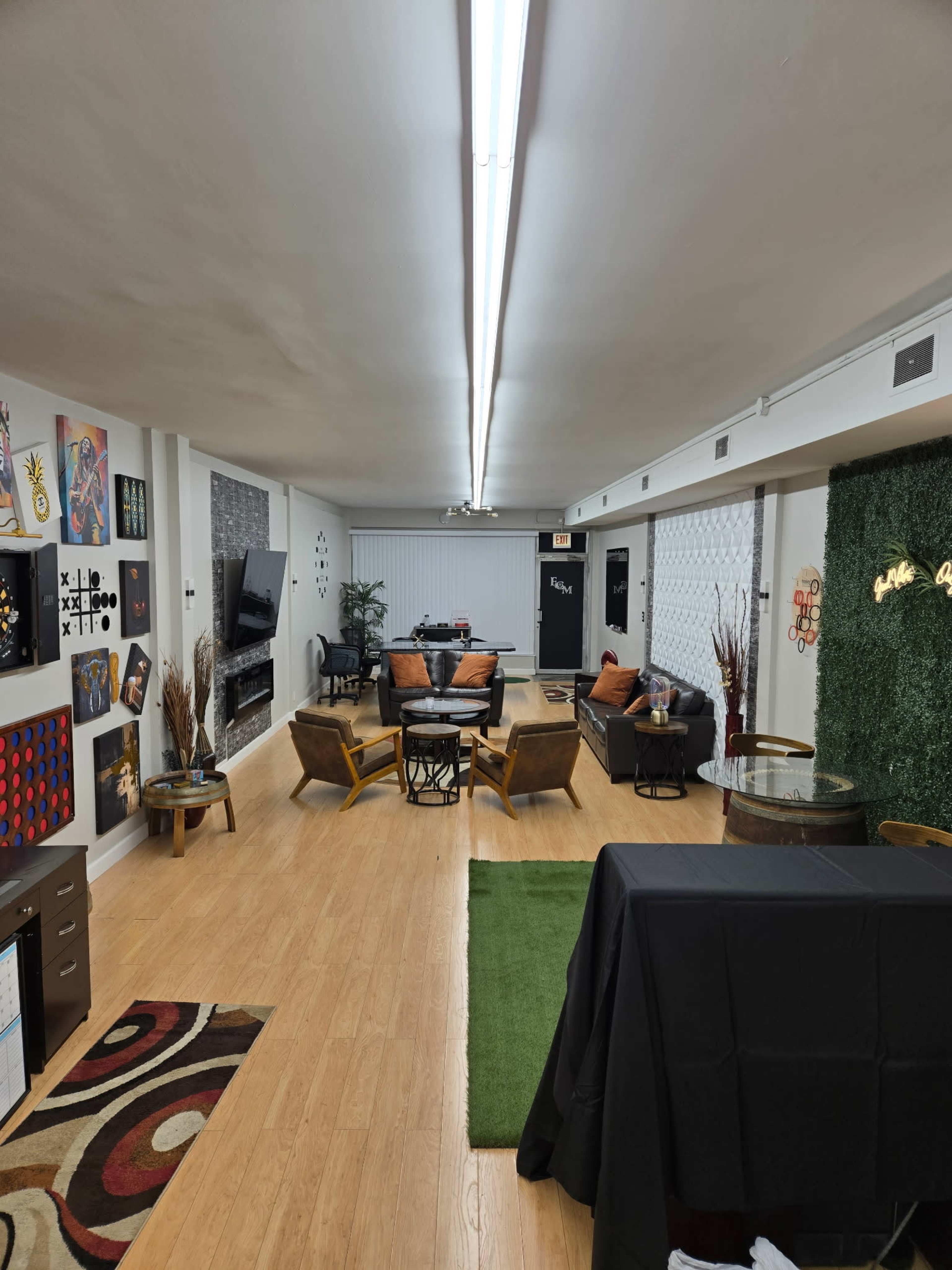 The image shows a spacious, modern room furnished with stylish seating, a decorative wall, and various artworks displayed.