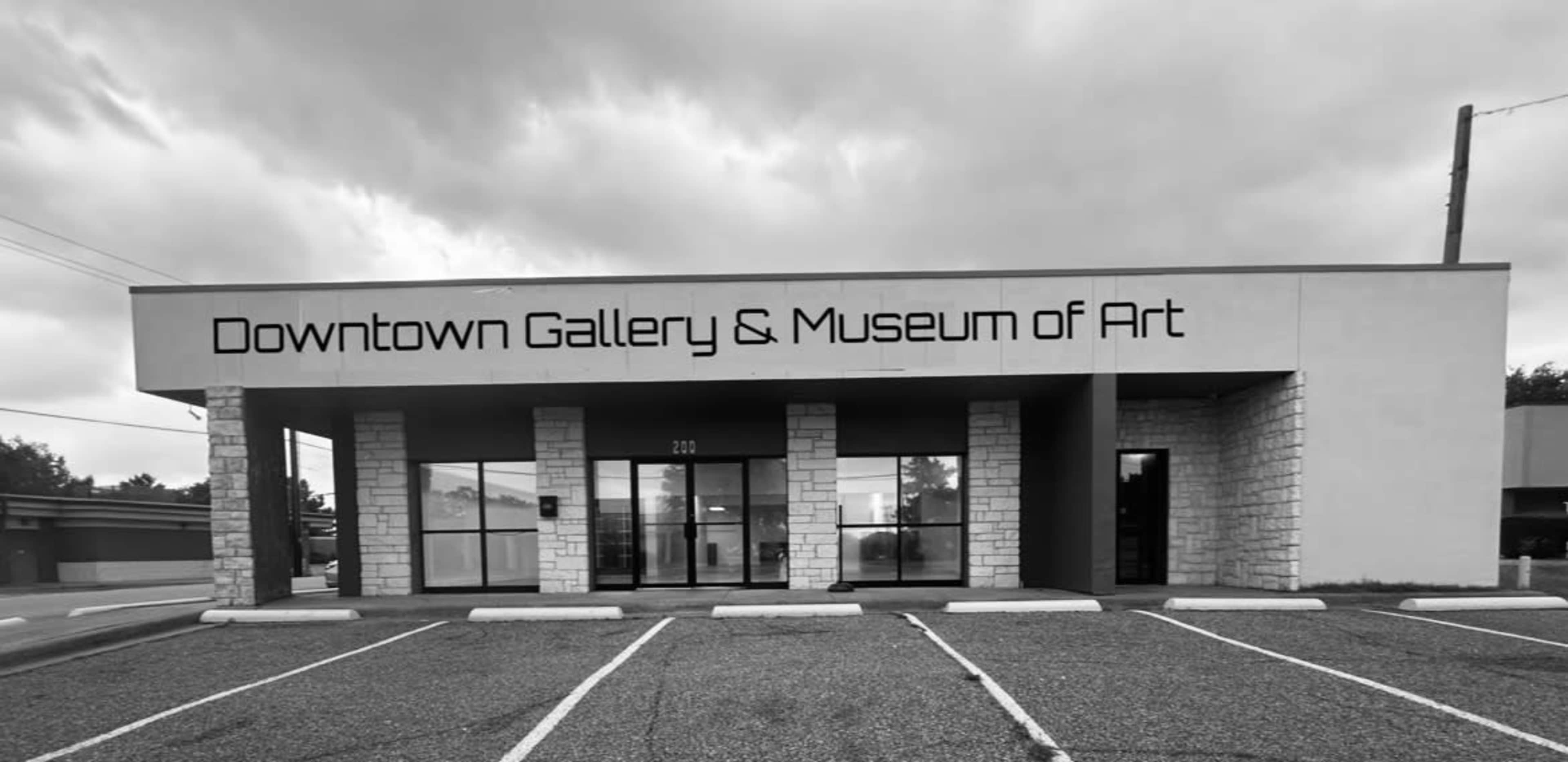 The image shows a modern building labeled "Downtown Gallery & Museum of Art," featuring large windows and a partially cloudy sky above.