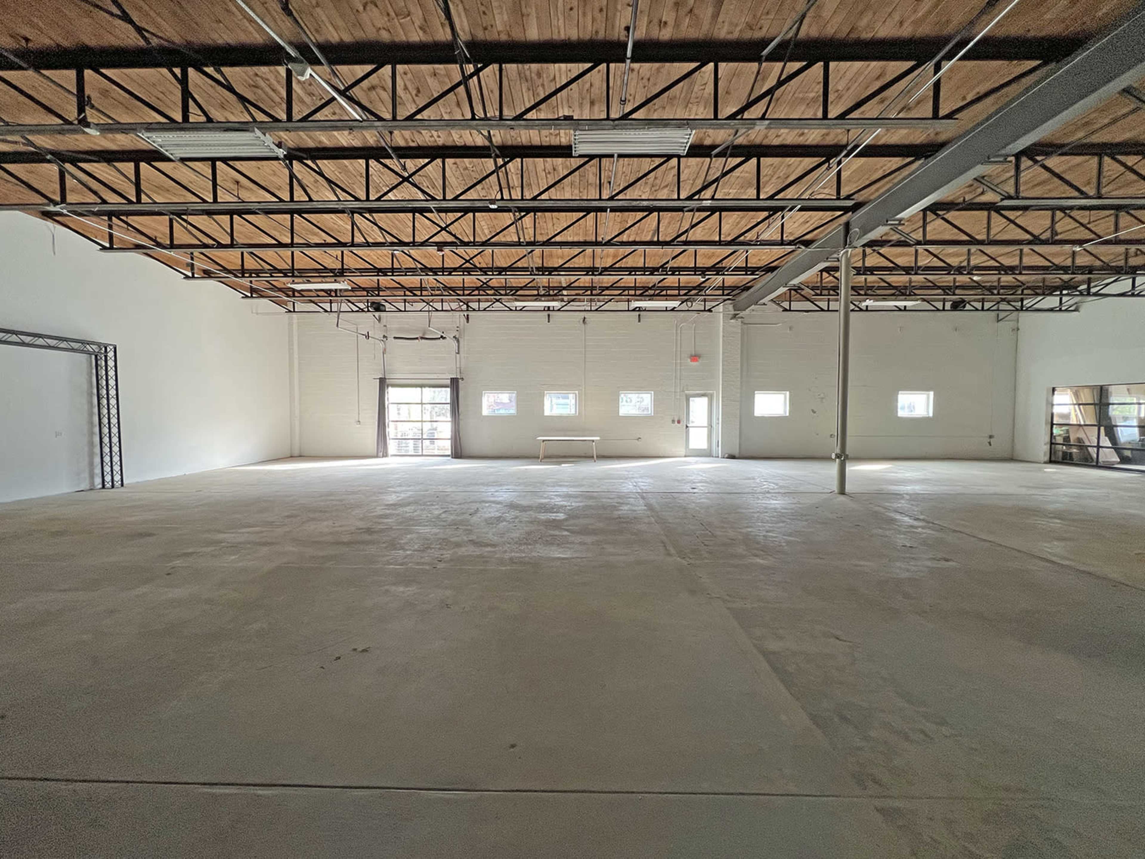 A large, empty warehouse space with a concrete floor and exposed beams.