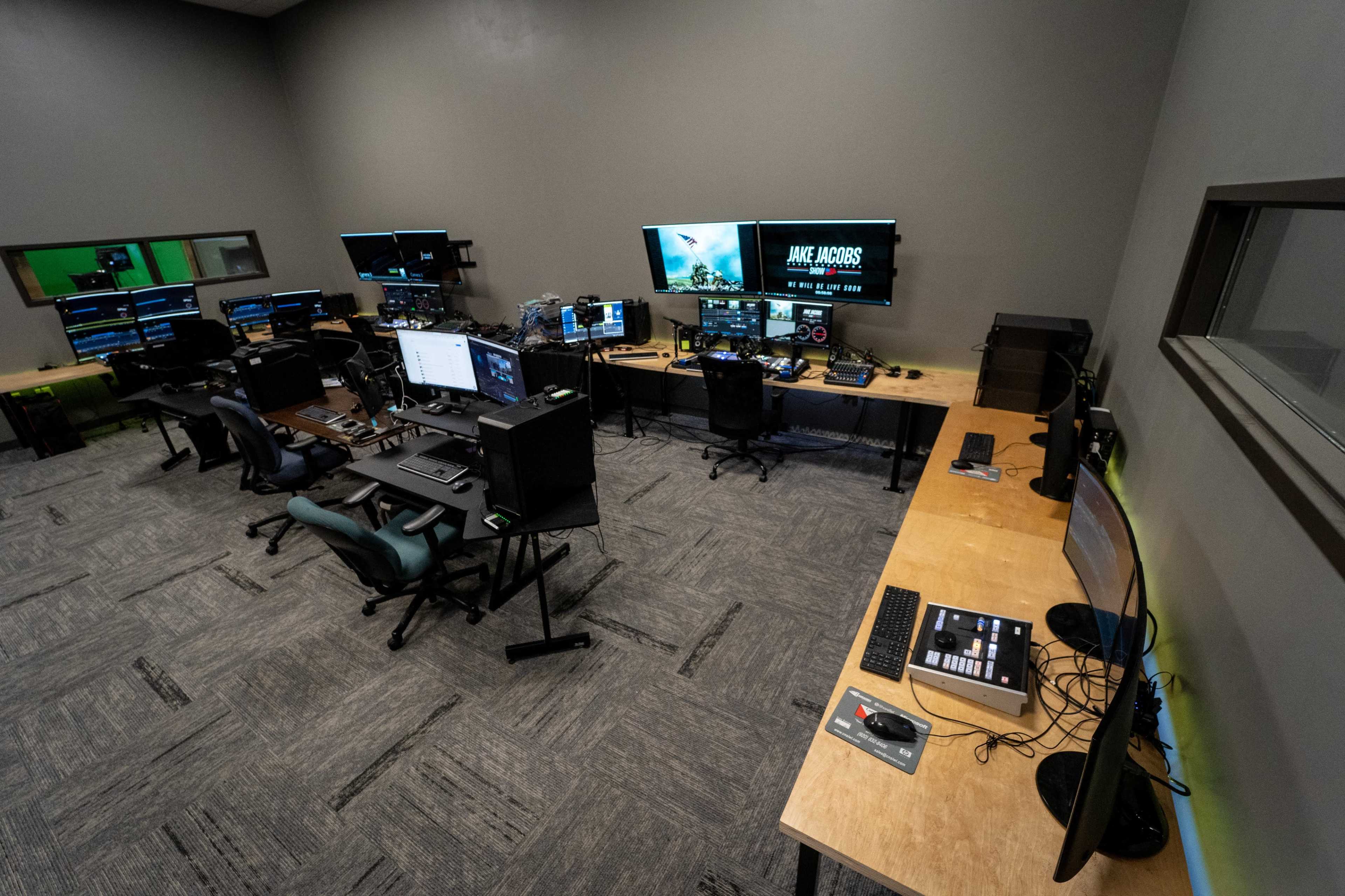 The image shows a modern control room equipped with multiple computer stations and large monitors displaying various data and images.